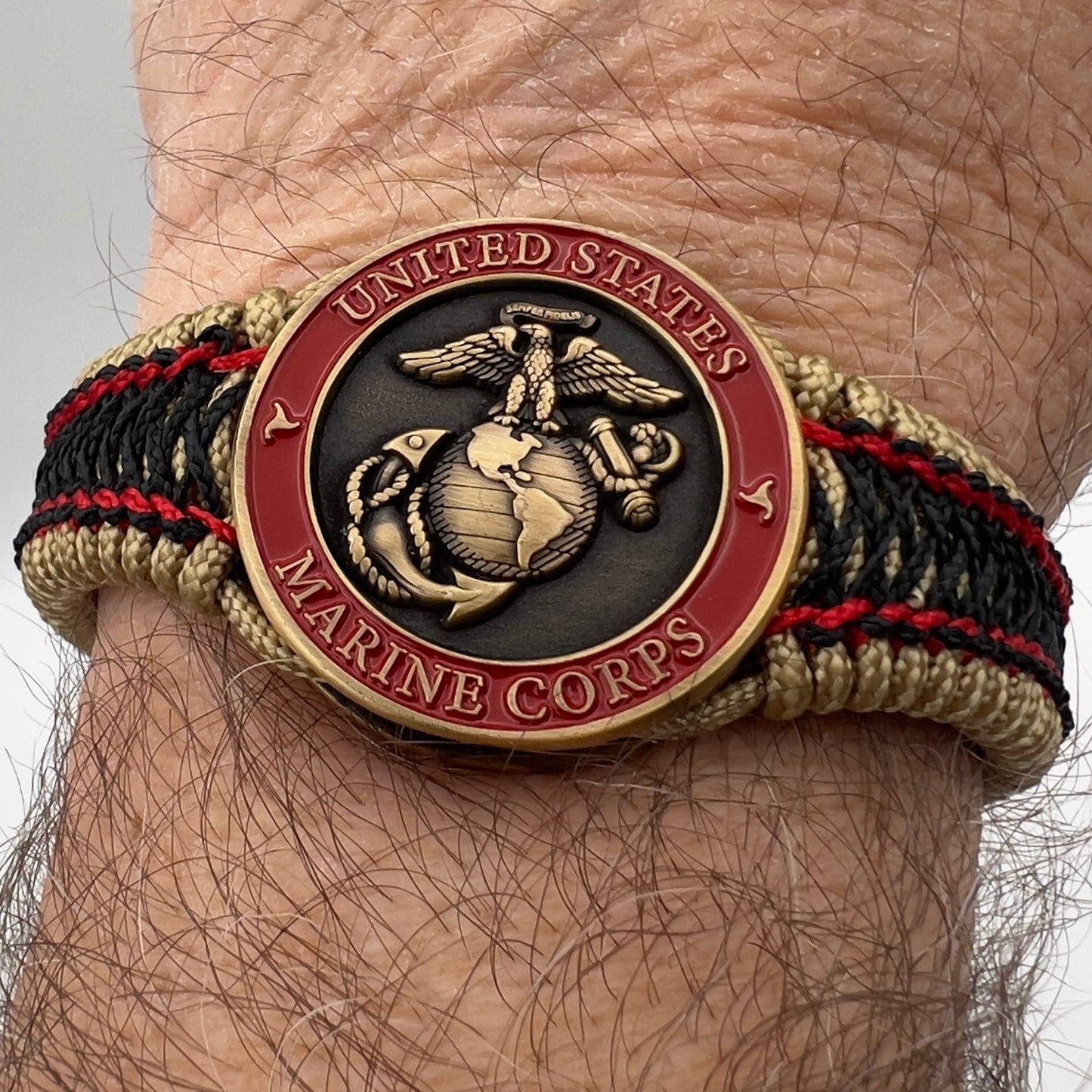 Thin, narrow, very thin and flexible and comfortable braided United States Marine Corps bracelet featuring a 24K antique gold plated USMC Eagle Globe and Anchor medallion, a gold Cobra style tactical buckle and woven with gold Type-1 paracord and Imperial Red and Black nano cord.