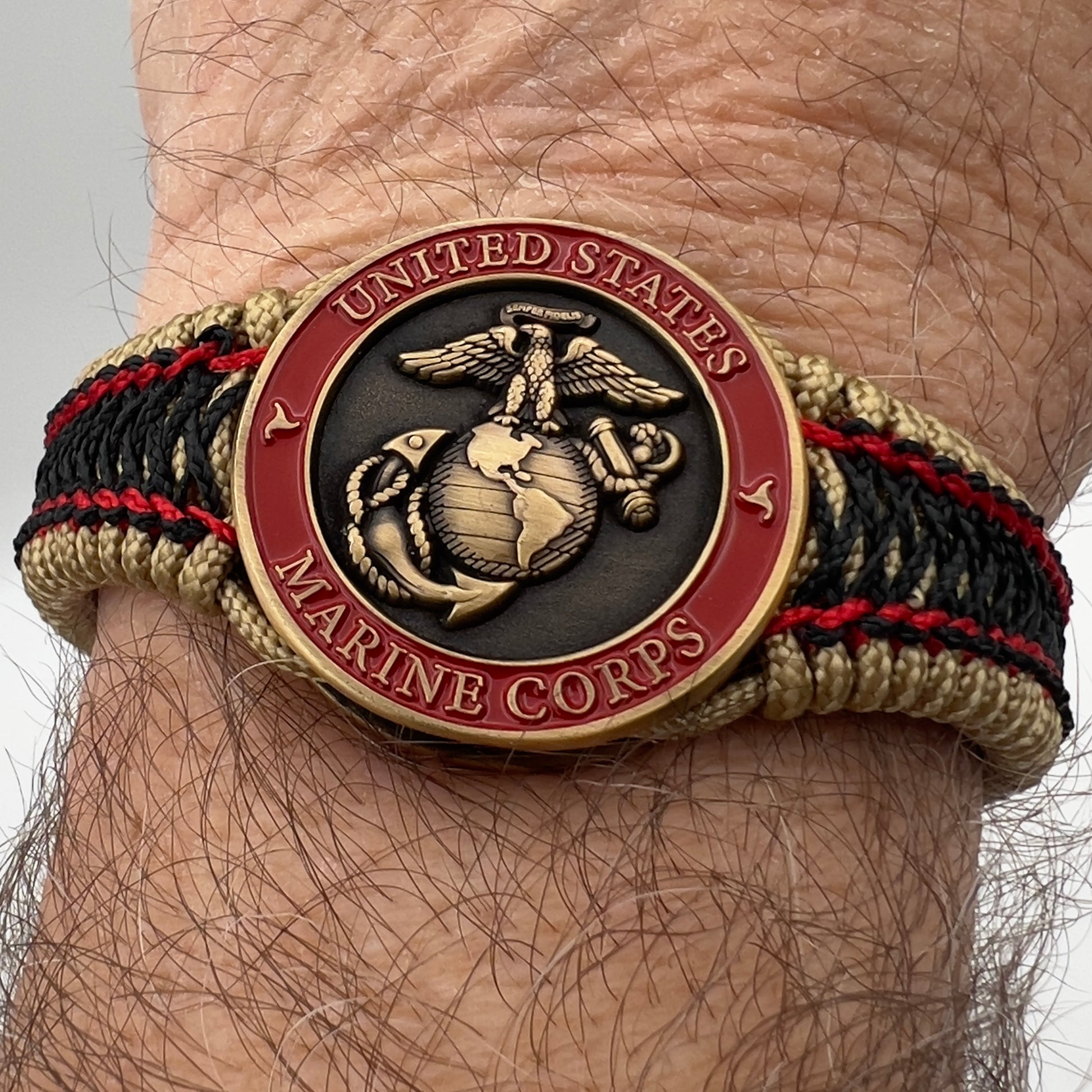 Thin, narrow, very thin and flexible and comfortable braided United States Marine Corps bracelet featuring a 24K antique gold plated USMC Eagle Globe and Anchor medallion, a gold Cobra style tactical buckle and woven with gold Type-1 paracord and Imperial Red and Black nano cord.