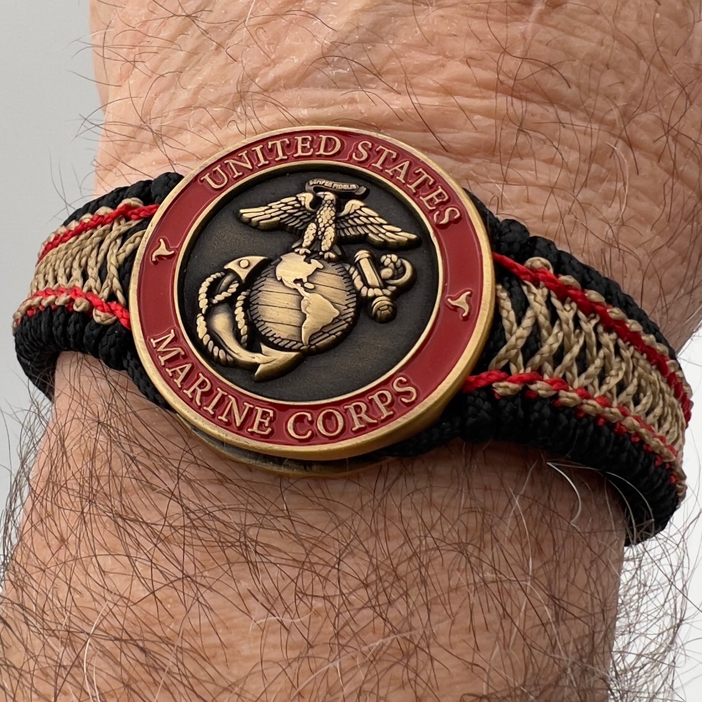 Thin, narrow, very thin and flexible and comfortable braided United States Marine Corps bracelet featuring a 24K antique gold plated USMC Eagle Globe and Anchor medallion, a black Cobra style tactical buckle and woven with black Type-1 paracord and Imperial Red and GOld nano cord.