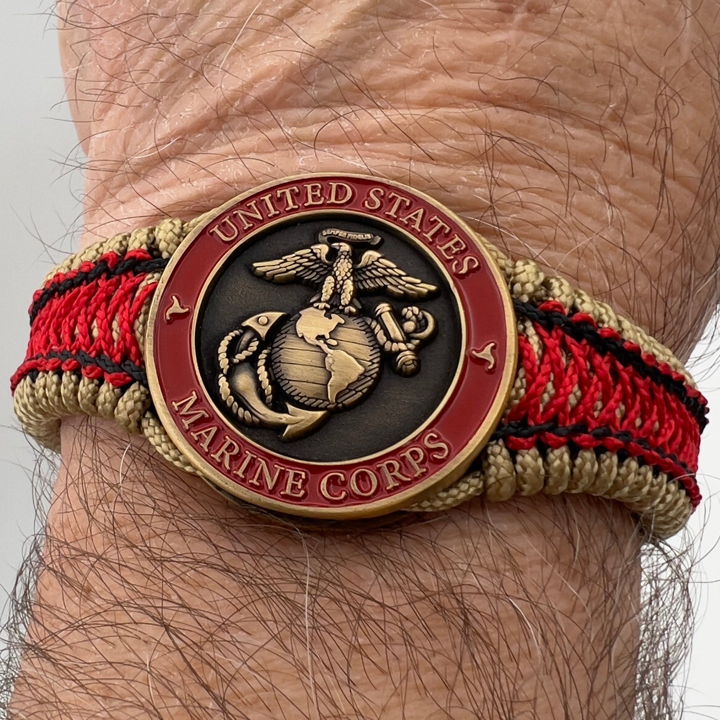 Thin, narrow, very thin and flexible and comfortable braided United States Marine Corps bracelet featuring a 24K antique gold plated USMC Eagle Globe and Anchor medallion, a gold Cobra style tactical buckle and woven with gold Type-1 paracord and Imperial Red and Black nano cord.
