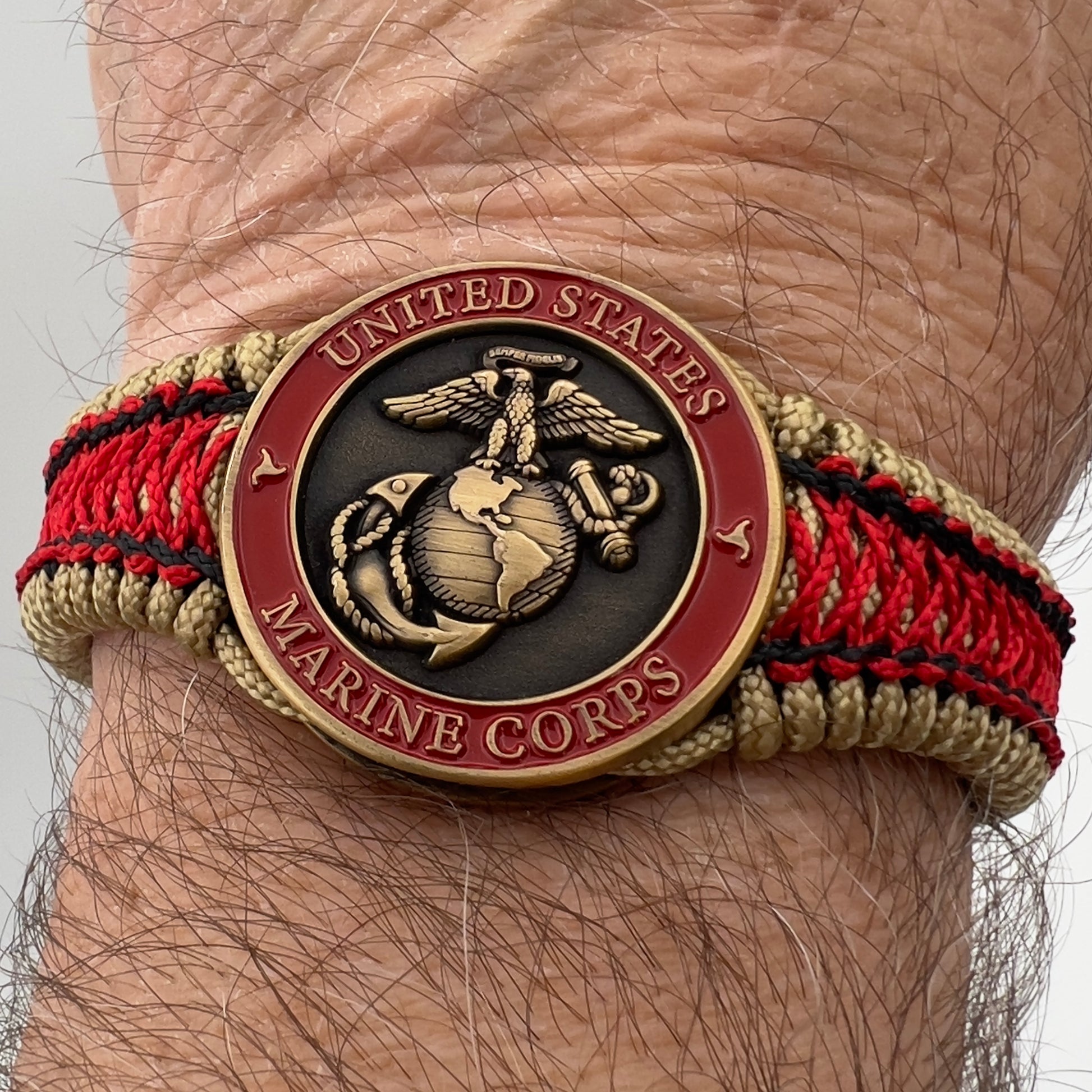 Thin, narrow, very thin and flexible and comfortable braided United States Marine Corps bracelet featuring a 24K antique gold plated USMC Eagle Globe and Anchor medallion, a gold Cobra style tactical buckle and woven with gold Type-1 paracord and Imperial Red and Black nano cord.
