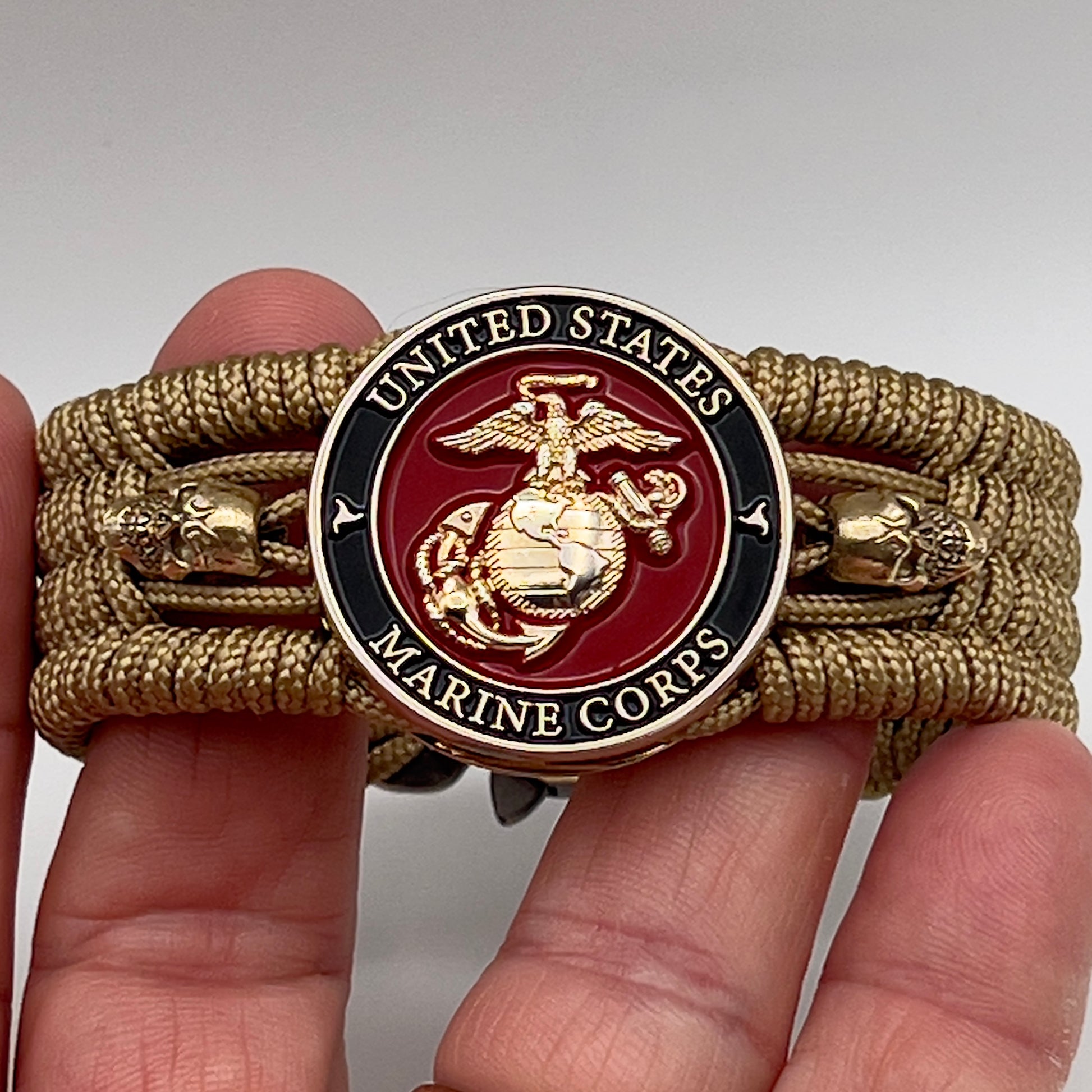 Thin, medium width, flexible and comfortable braided United States Marine Corps bracelet featuring a 24K gold plated USMC officer Eagle Globe and Anchor medallion, two gold plated skulls, a gold Cobra style tactical buckle and woven with gold Type-1 paracord.