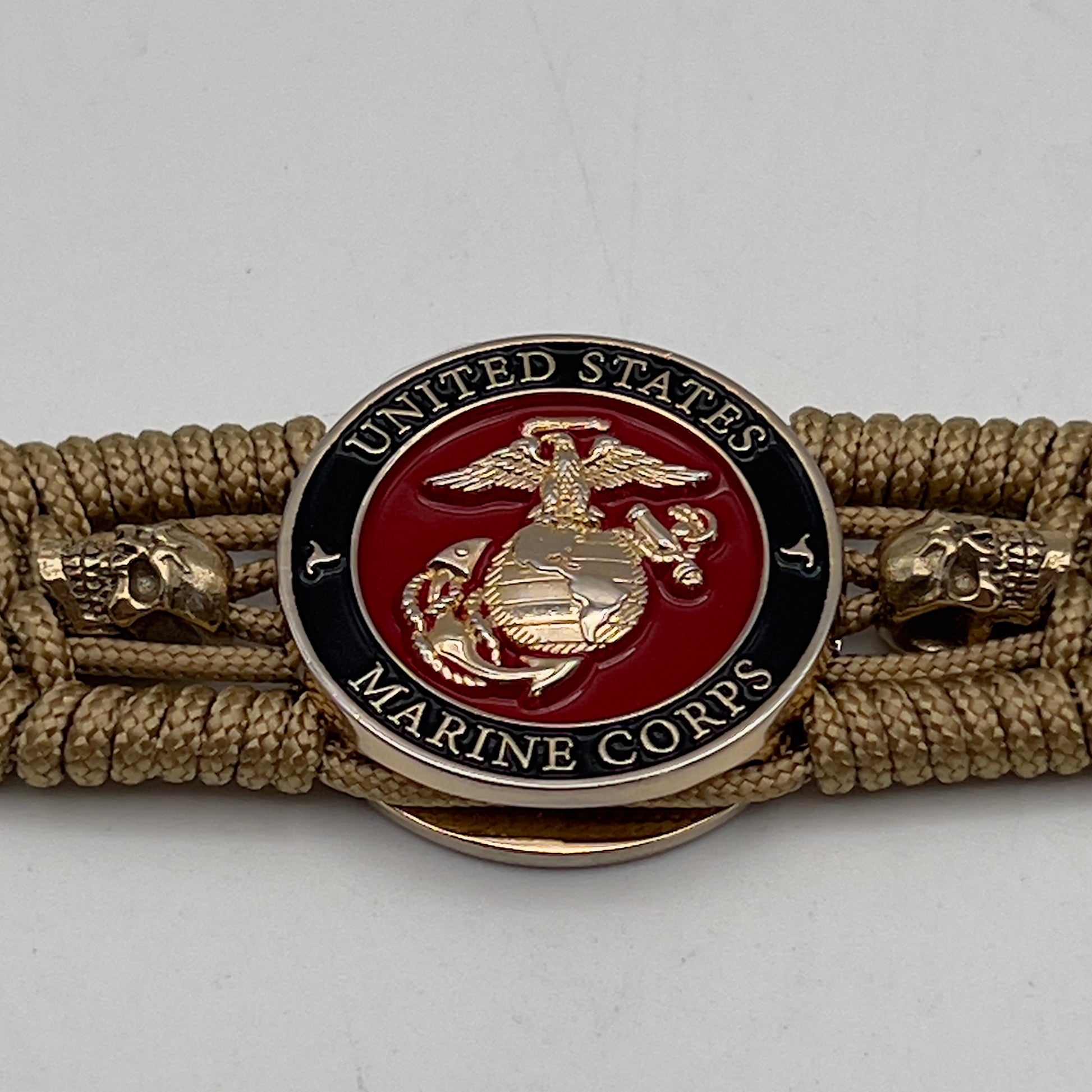 Thin, medium width, flexible and comfortable braided United States Marine Corps bracelet featuring a 24K gold plated USMC officer Eagle Globe and Anchor medallion, two gold plated skulls, a gold Cobra style tactical buckle and woven with gold Type-1 paracord.