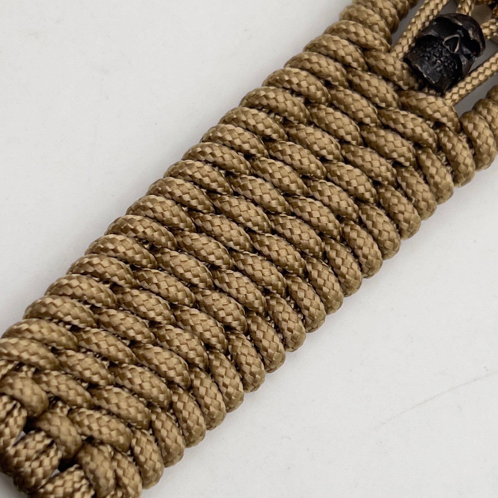 Thin, medium width, flexible and comfortable braided United States Marine Corps bracelet featuring a 24K gold plated USMC officer Eagle Globe and Anchor medallion, two black micro skulls, a gold Cobra style tactical buckle and woven with gold Type-1 paracord.