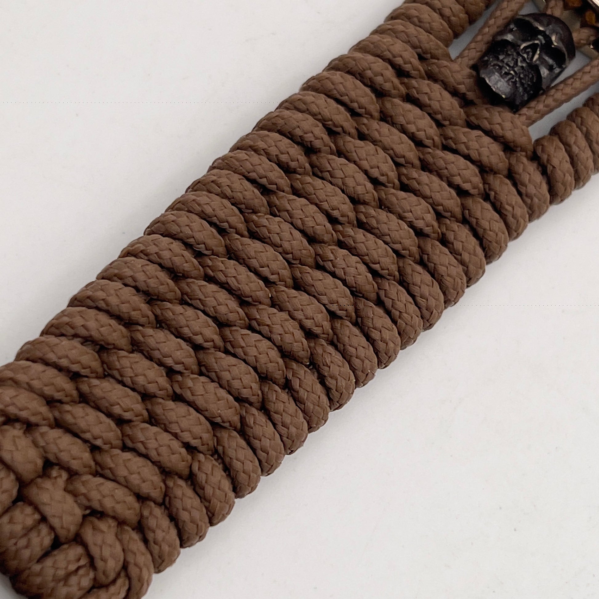 Thin, medium width, flexible and comfortable braided United States Marine Corps bracelet featuring a 24K gold plated USMC officer Eagle Globe and Anchor medallion, two black micro skulls, a black Cobra style tactical buckle and woven with Coyote Brown Type-1 paracord.