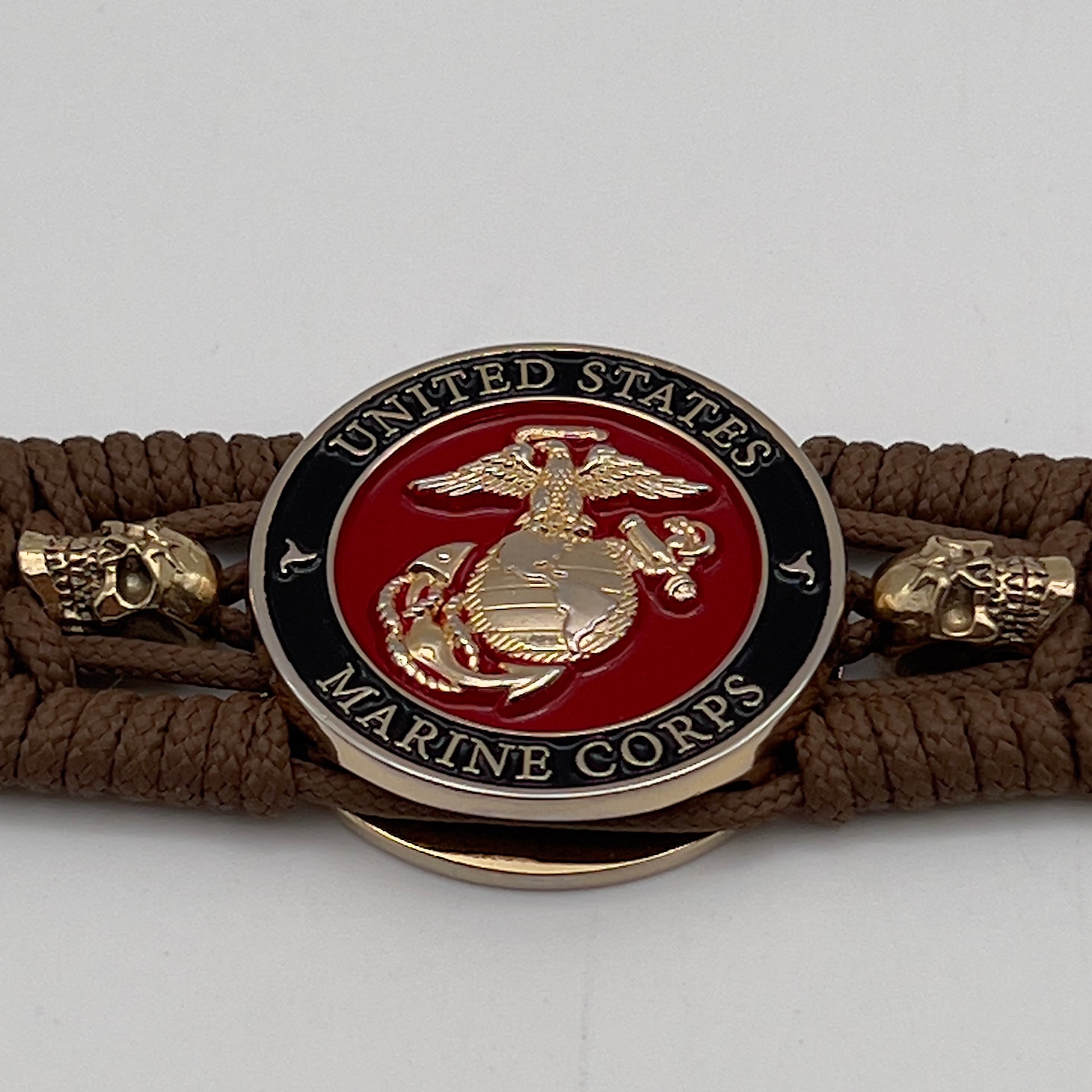 Thin, medium width, flexible and comfortable braided United States Marine Corps bracelet featuring a 24K gold plated USMC officer Eagle Globe and Anchor medallion, two gold plated skulls, a gold Cobra style tactical buckle and woven with Coyote Brown Type-1 paracord.