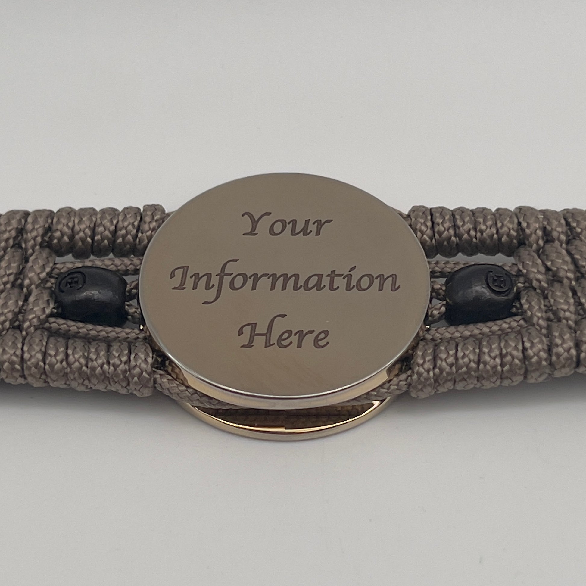 Thin, medium width, flexible and comfortable braided United States Marine Corps bracelet featuring a 24K gold plated USMC officer Eagle Globe and Anchor medallion, two black skulls, a black Cobra style tactical buckle and woven with tan Type-1 paracord.