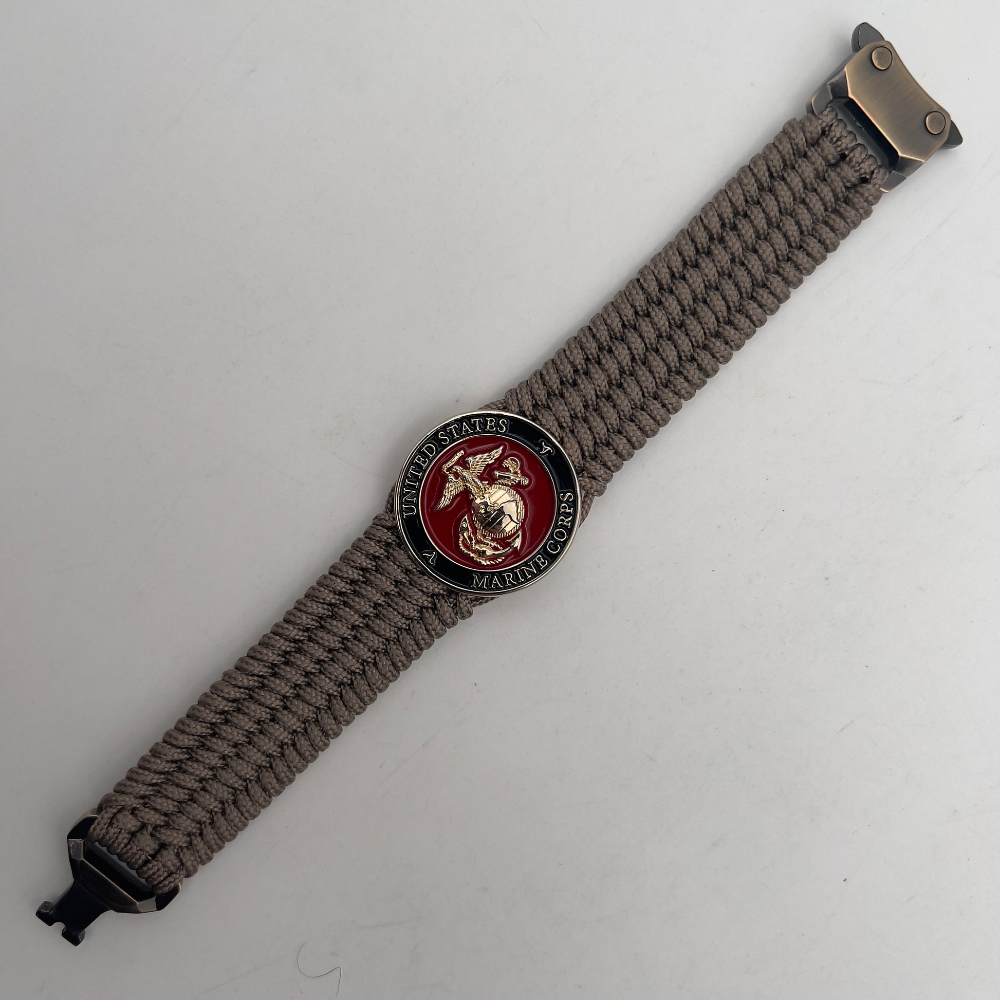 Thin, medium width, flexible and comfortable braided United States Marine Corps bracelet featuring a 24K gold plated USMC officer Eagle Globe and Anchor medallion, a gold Cobra style tactical buckle and woven with Tan Type-1 paracord.