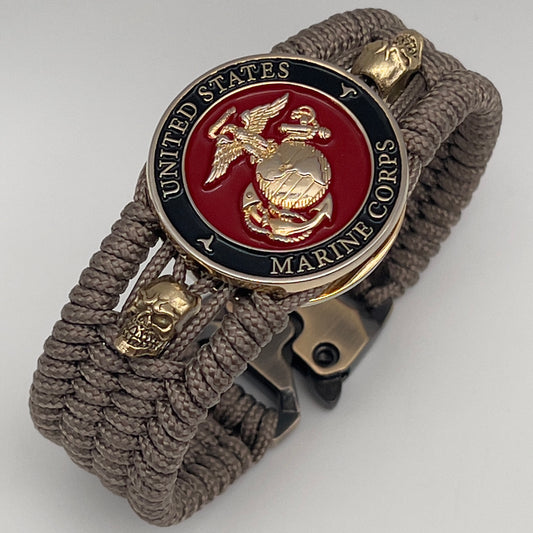 Thin, medium width, flexible and comfortable braided United States Marine Corps bracelet featuring a 24K gold plated USMC officer Eagle Globe and Anchor medallion, two gold plated skulls, a gold Cobra style tactical buckle and woven with Tan Type-1 paracord.