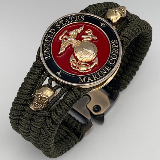 Thin, medium width, flexible and comfortable braided United States Marine Corps bracelet featuring a 24K gold plated USMC officer Eagle Globe and Anchor medallion, two gold plated skulls, a gold Cobra style tactical buckle and woven with Olive Drab Type-1 paracord.