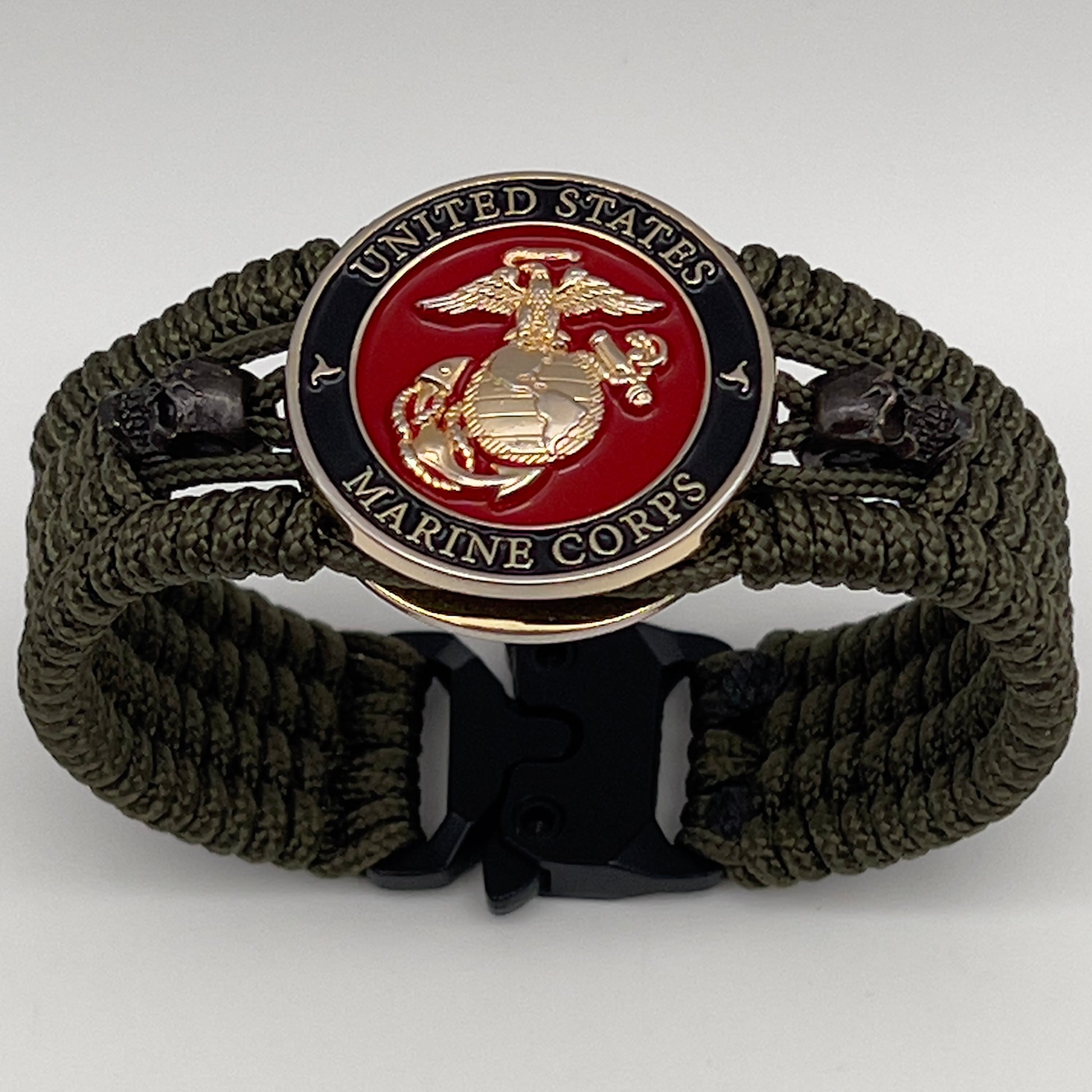 Thin, medium width, flexible and comfortable braided United States Marine Corps bracelet featuring a 24K gold plated USMC officer Eagle Globe and Anchor medallion, two black micro skulls, a black Cobra style tactical buckle and woven with Olive Drab Type-1 paracord.