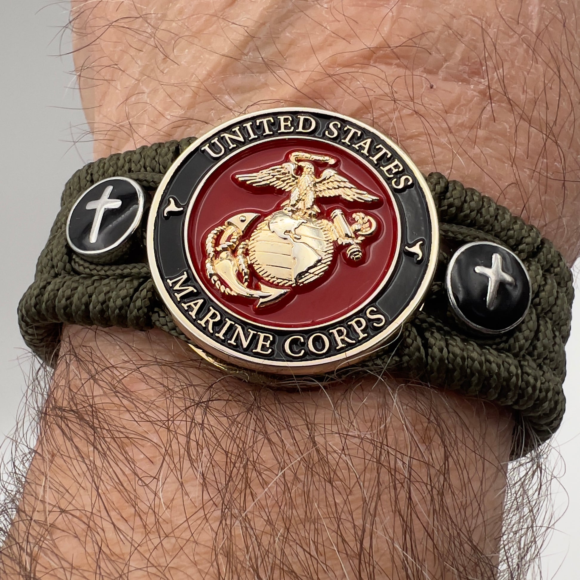 Thin, medium width, flexible and comfortable braided United States Marine Corps bracelet featuring a 24K gold plated USMC officer Eagle Globe and Anchor medallion, two Christian crosses, a black Cobra style tactical buckle and woven with Olive Drab Type-1 paracord.