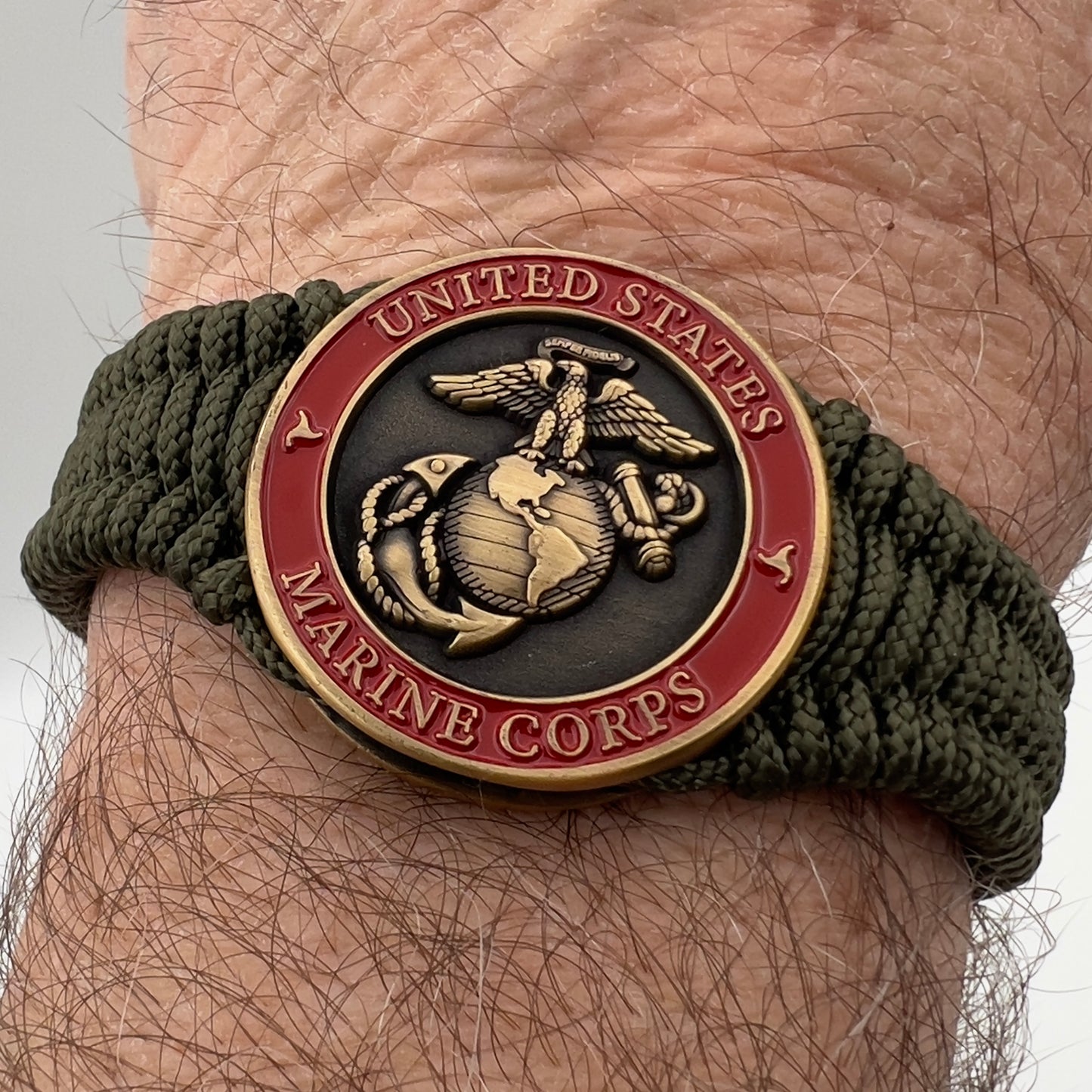Thin, narrow, flexible and comfortable braided United States Marine Corps bracelet featuring a 24K antique gold plated USMC Eagle Globe and Anchor medallion, a gold Cobra style tactical buckle and woven with Olive Drab Type-1 paracord.