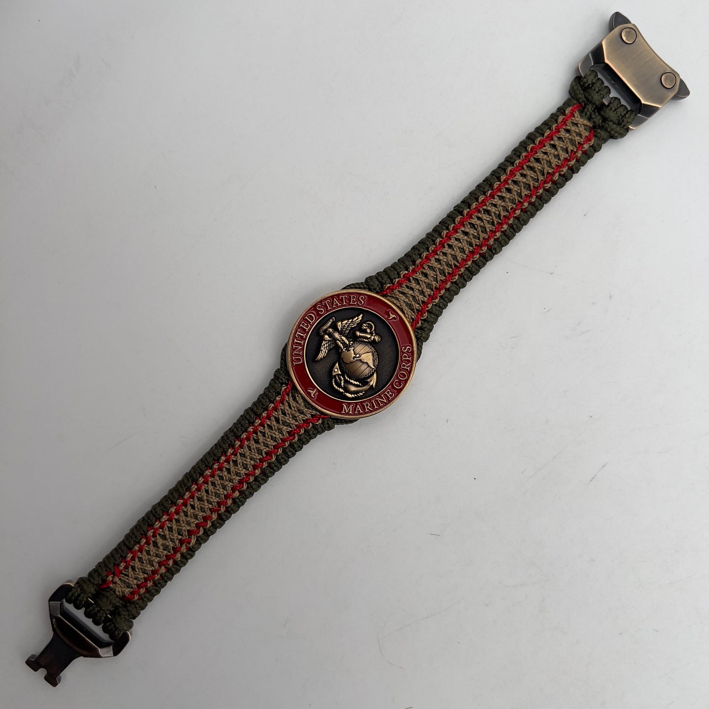 Thin, narrow, flexible and comfortable braided United States Marine Corps bracelet featuring a 24K antique gold plated USMC Eagle Globe and Anchor medallion, a gold Cobra style tactical buckle and woven with Olive Drab Type-1 paracord and Imperial Red and Gold nano cord.