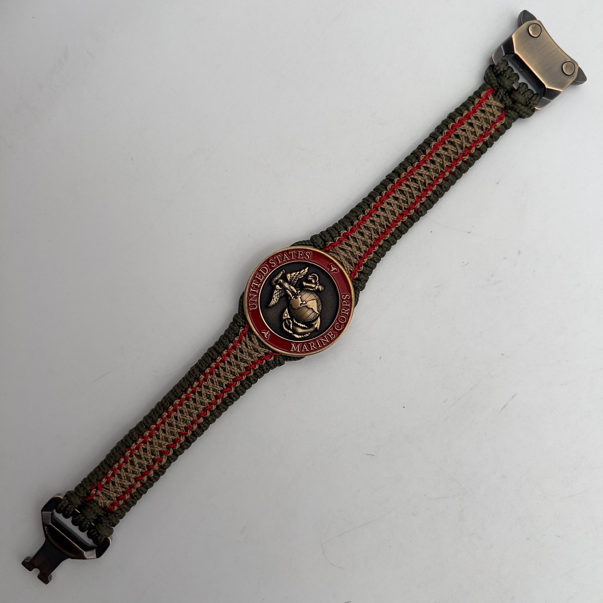 Thin, narrow, flexible and comfortable braided United States Marine Corps bracelet featuring a 24K antique gold plated USMC Eagle Globe and Anchor medallion, a gold Cobra style tactical buckle and woven with Olive Drab Type-1 paracord and Imperial Red and Gold nano cord.