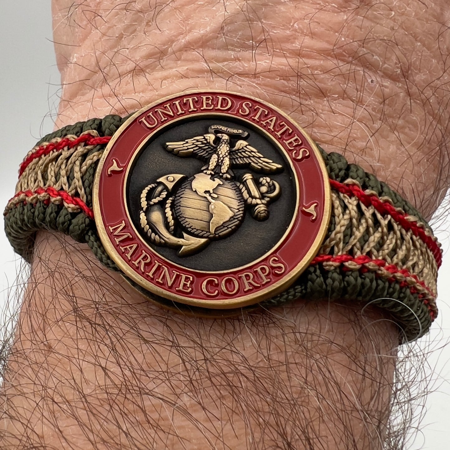 Thin, narrow, flexible and comfortable braided United States Marine Corps bracelet featuring a 24K antique gold plated USMC Eagle Globe and Anchor medallion, a gold Cobra style tactical buckle and woven with Olive Drab Type-1 paracord and Imperial Red and Gold nano cord.
