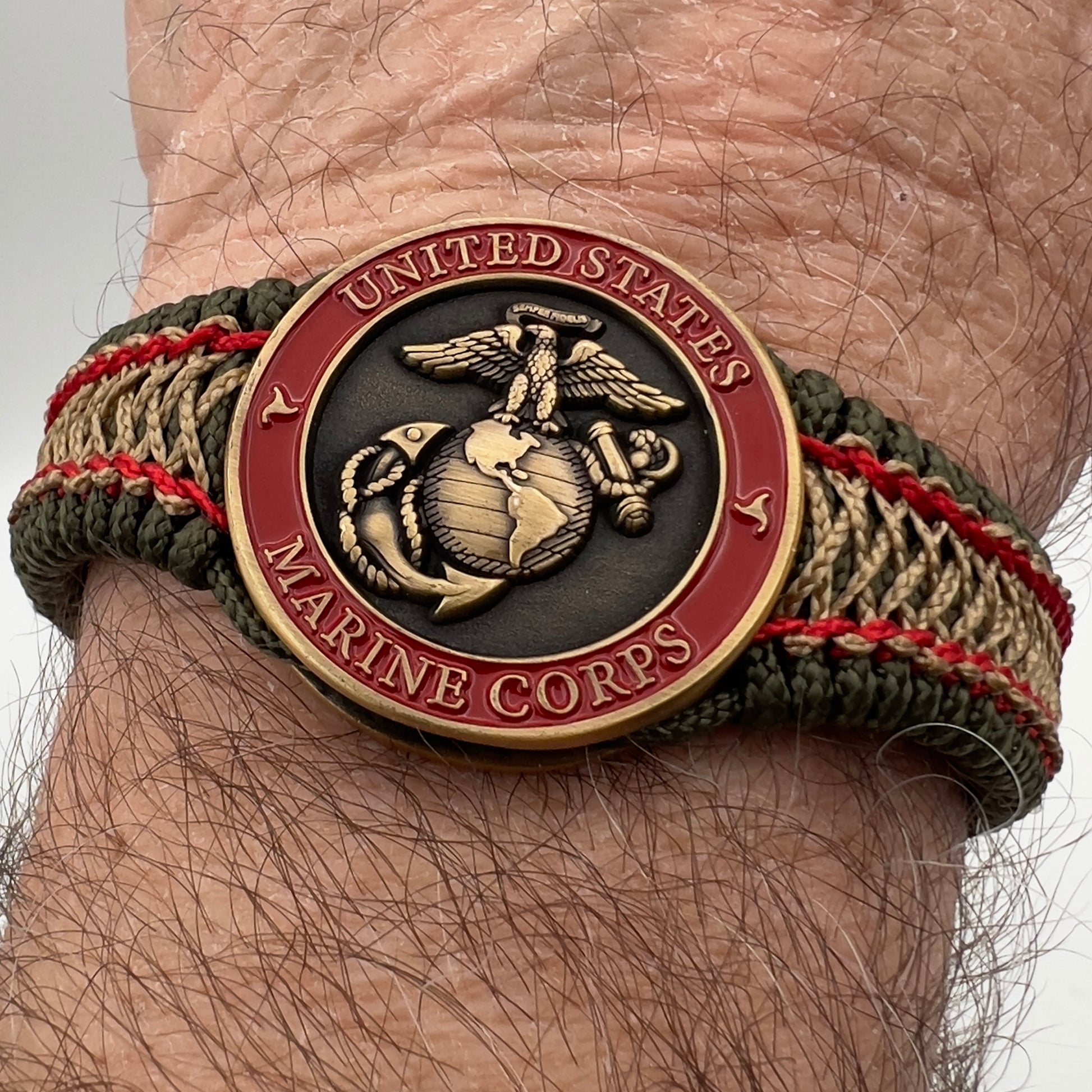 Thin, narrow, flexible and comfortable braided United States Marine Corps bracelet featuring a 24K antique gold plated USMC Eagle Globe and Anchor medallion, a gold Cobra style tactical buckle and woven with Olive Drab Type-1 paracord and Imperial Red and Gold nano cord.