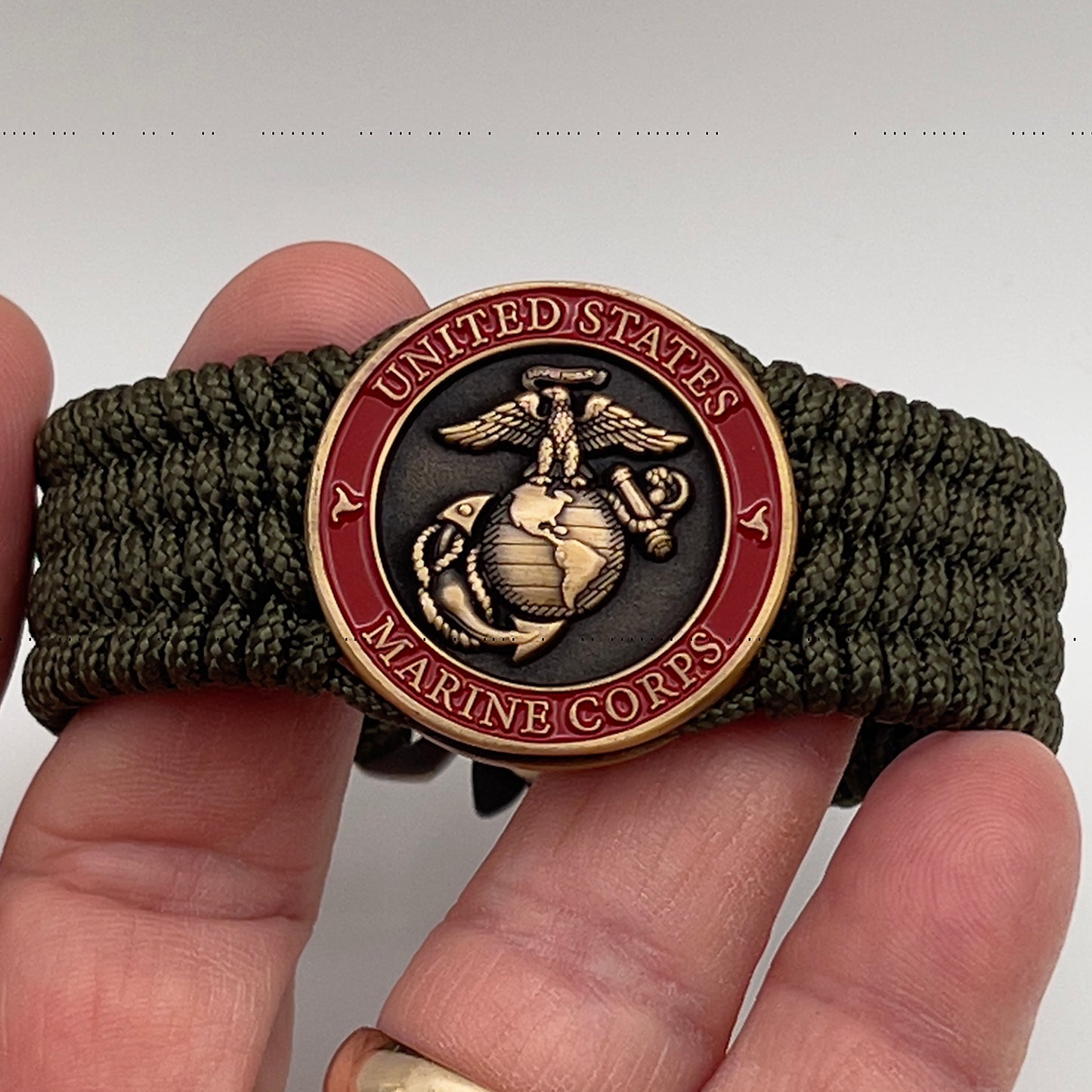 Thin, medium wide, flexible and comfortable braided United States Marine Corps bracelet featuring a 24K antique gold plated USMC Eagle Globe and Anchor medallion, a gold Cobra style tactical buckle and woven with Olive Drab Type-1 paracord.