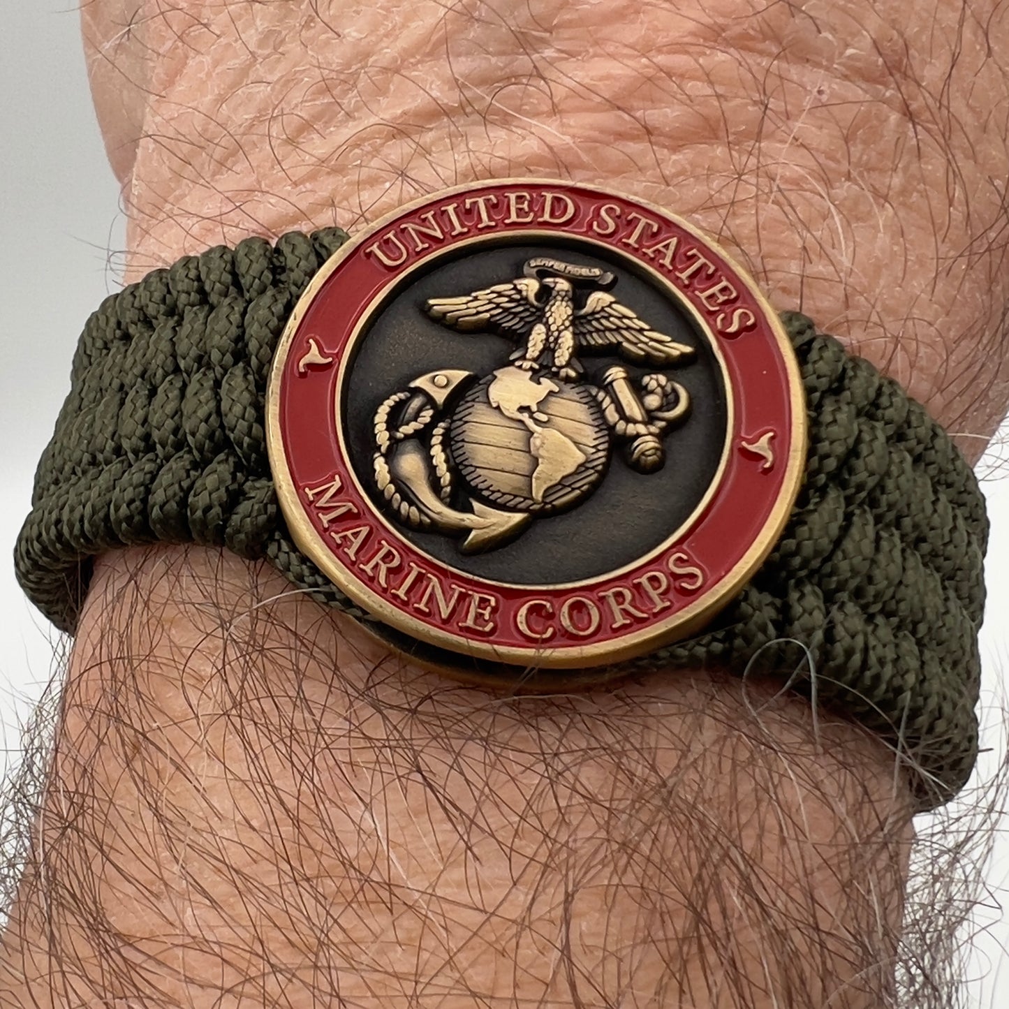 Thin, medium wide, flexible and comfortable braided United States Marine Corps bracelet featuring a 24K antique gold plated USMC Eagle Globe and Anchor medallion, a gold Cobra style tactical buckle and woven with Olive Drab Type-1 paracord.