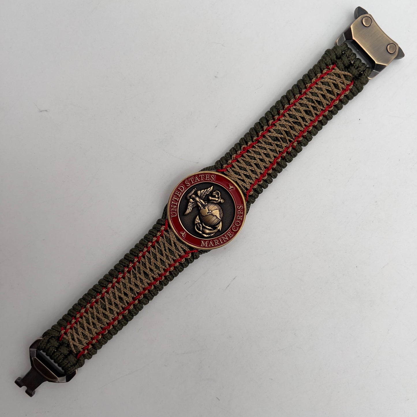 Thin, medium width, flexible and comfortable braided United States Marine Corps bracelet featuring a 24K antique gold plated USMC Eagle Globe and Anchor medallion, a gold Cobra style tactical buckle and woven with Olive Drab Type-1 paracord and Imperial Red and Gold nano cord.