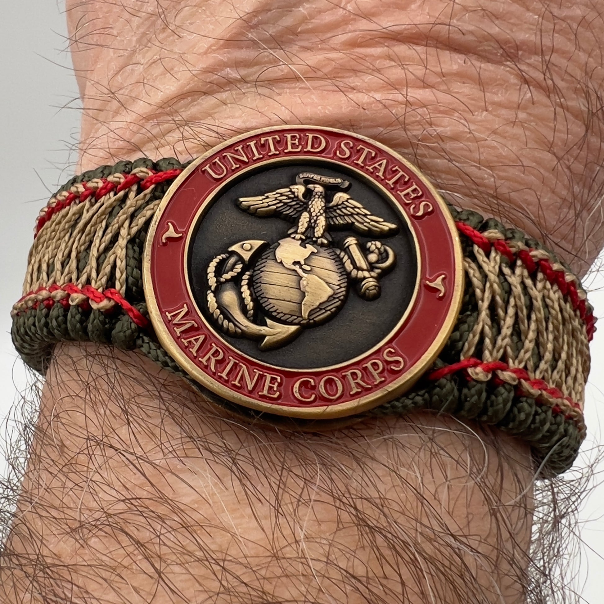 Thin, medium width, flexible and comfortable braided United States Marine Corps bracelet featuring a 24K antique gold plated USMC Eagle Globe and Anchor medallion, a gold Cobra style tactical buckle and woven with Olive Drab Type-1 paracord and Imperial Red and Gold nano cord.