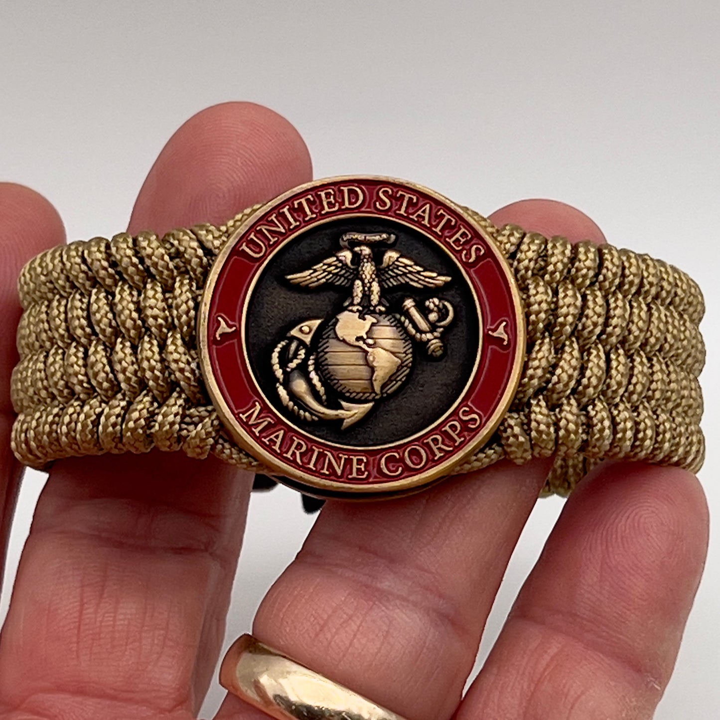Thin, wide, flexible and comfortable braided United States Marine Corps bracelet featuring a 24K antique gold plated USMC Eagle Globe and Anchor medallion, a gold Cobra style tactical buckle and woven with gold Type-1 paracord.