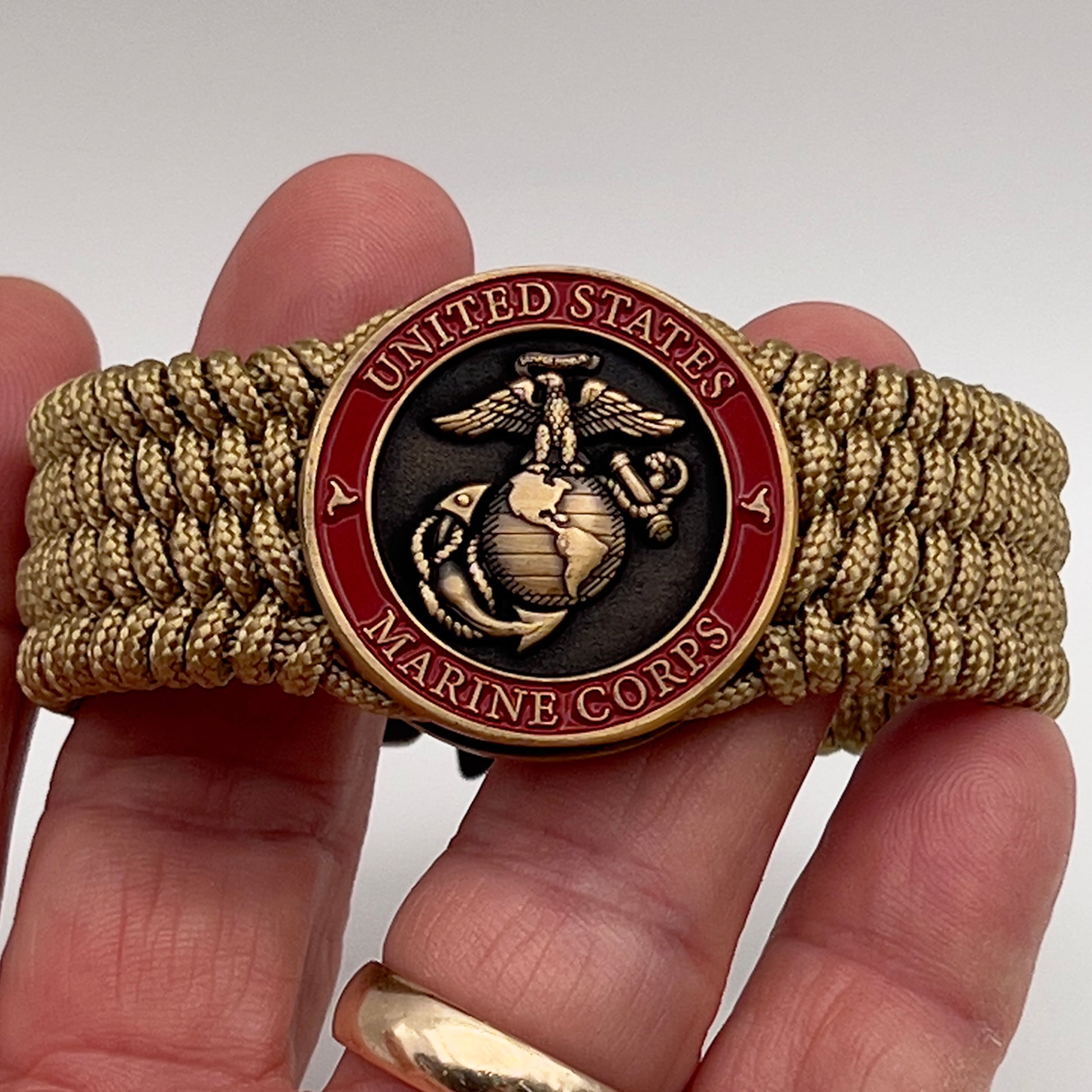 Thin, wide, flexible and comfortable braided United States Marine Corps bracelet featuring a 24K antique gold plated USMC Eagle Globe and Anchor medallion, a gold Cobra style tactical buckle and woven with gold Type-1 paracord.