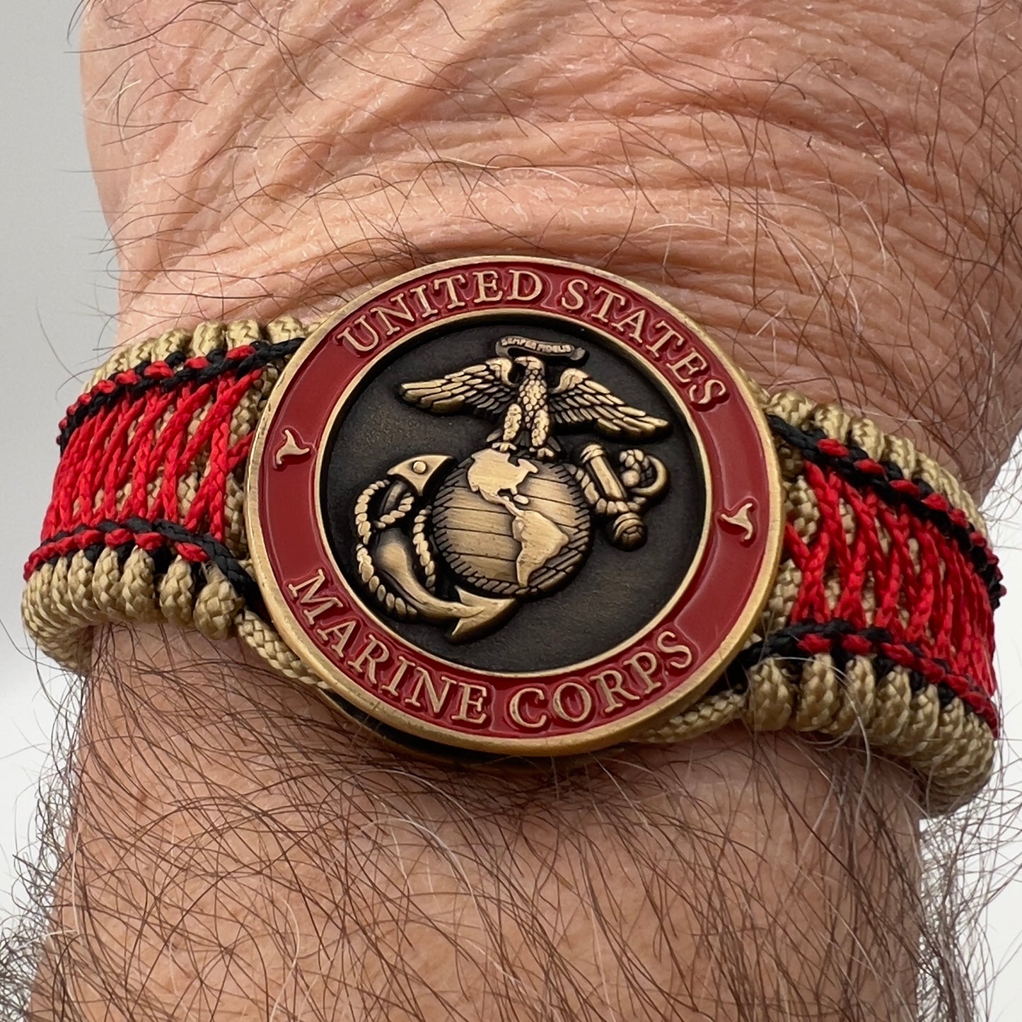 Thin, medium width, flexible and comfortable braided United States Marine Corps bracelet featuring a 24K antique gold plated USMC Eagle Globe and Anchor medallion, a gold Cobra style tactical buckle and woven with gold Type-1 paracord and Imperial Red and Black nano cord.