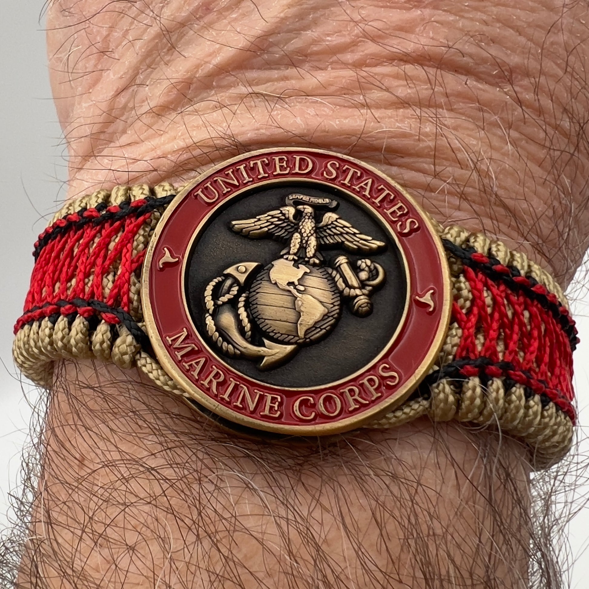 Thin, medium width, flexible and comfortable braided United States Marine Corps bracelet featuring a 24K antique gold plated USMC Eagle Globe and Anchor medallion, a gold Cobra style tactical buckle and woven with gold Type-1 paracord and Imperial Red and Black nano cord.