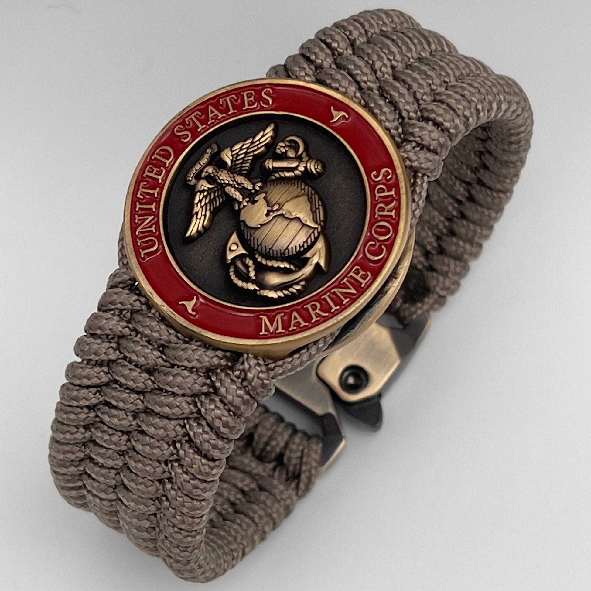Thin, medium wide, flexible and comfortable braided United States Marine Corps bracelet featuring a 24K antique gold plated USMC Eagle Globe and Anchor medallion, a gold Cobra style tactical buckle and woven with Tan Type-1 paracord.