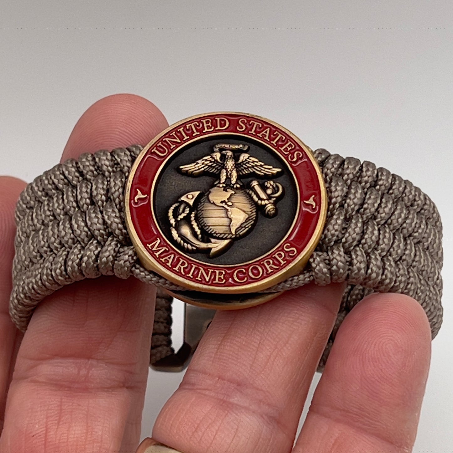 Thin, medium wide, flexible and comfortable braided United States Marine Corps bracelet featuring a 24K antique gold plated USMC Eagle Globe and Anchor medallion, a gold Cobra style tactical buckle and woven with Tan Type-1 paracord.