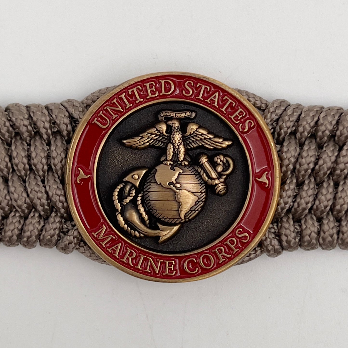 Thin, medium wide, flexible and comfortable braided United States Marine Corps bracelet featuring a 24K antique gold plated USMC Eagle Globe and Anchor medallion, a gold Cobra style tactical buckle and woven with Tan Type-1 paracord.