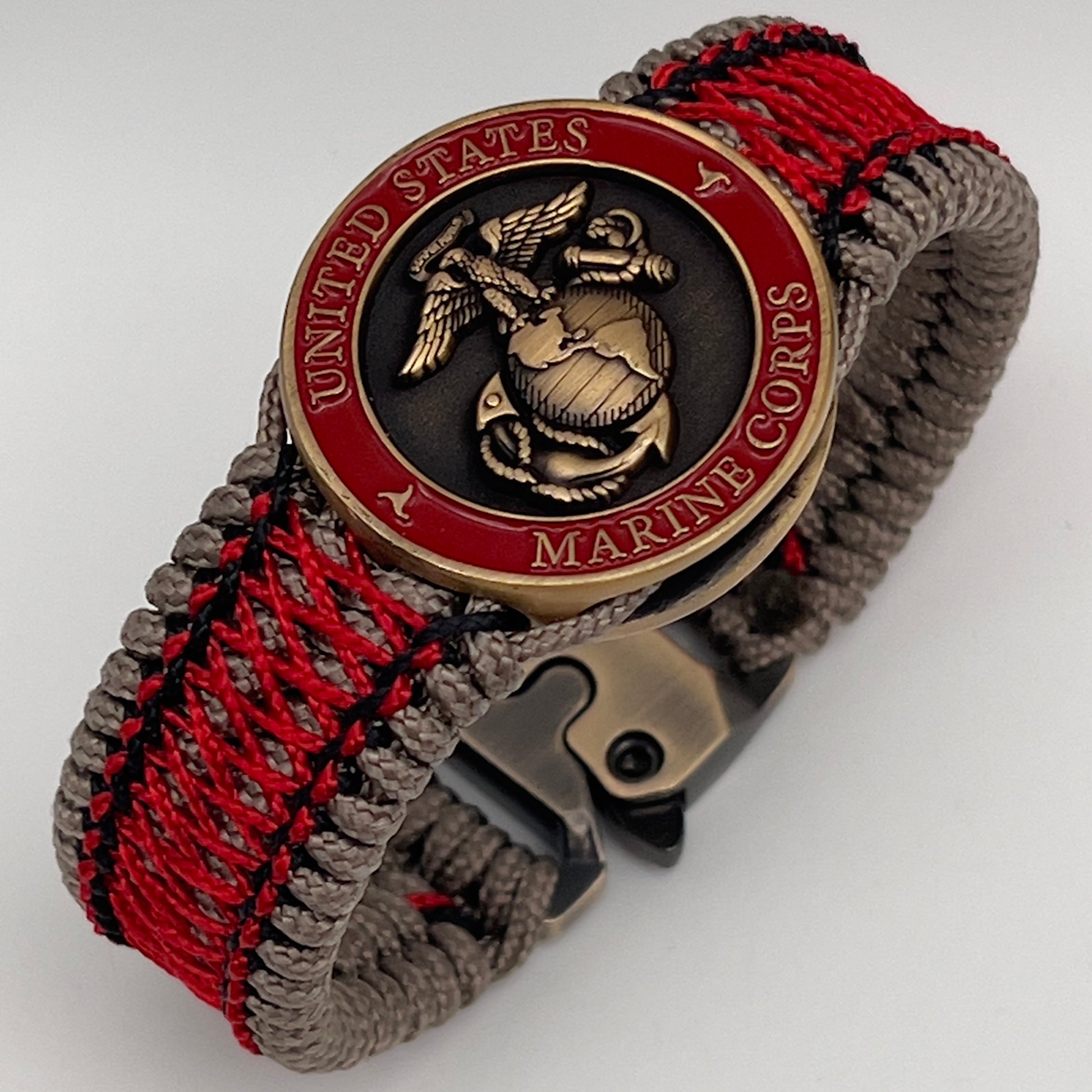 Thin, medium width, flexible and comfortable braided United States Marine Corps bracelet featuring a 24K antique gold plated USMC Eagle Globe and Anchor medallion, a gold Cobra style tactical buckle and woven with Tan Type-1 paracord and Imperial Red and Black nano cord.