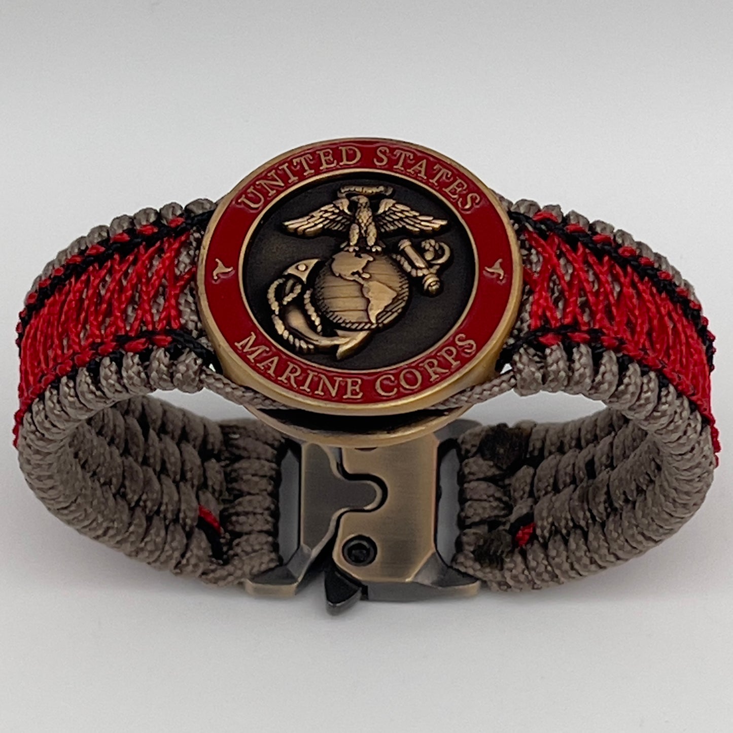 Thin, medium width, flexible and comfortable braided United States Marine Corps bracelet featuring a 24K antique gold plated USMC Eagle Globe and Anchor medallion, a gold Cobra style tactical buckle and woven with Tan Type-1 paracord and Imperial Red and Black nano cord.