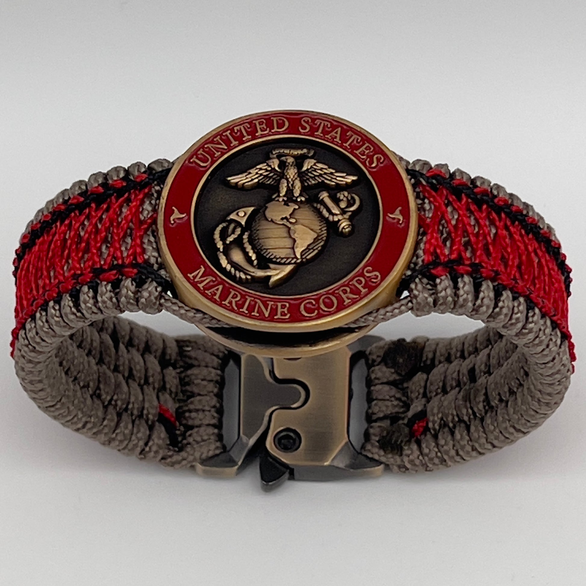 Thin, medium width, flexible and comfortable braided United States Marine Corps bracelet featuring a 24K antique gold plated USMC Eagle Globe and Anchor medallion, a gold Cobra style tactical buckle and woven with Tan Type-1 paracord and Imperial Red and Black nano cord.