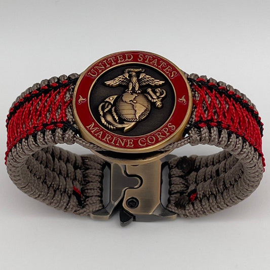Thin, medium width, flexible and comfortable braided United States Marine Corps bracelet featuring a 24K antique gold plated USMC Eagle Globe and Anchor medallion, a gold Cobra style tactical buckle and woven with Tan Type-1 paracord and Imperial Red and Black nano cord.