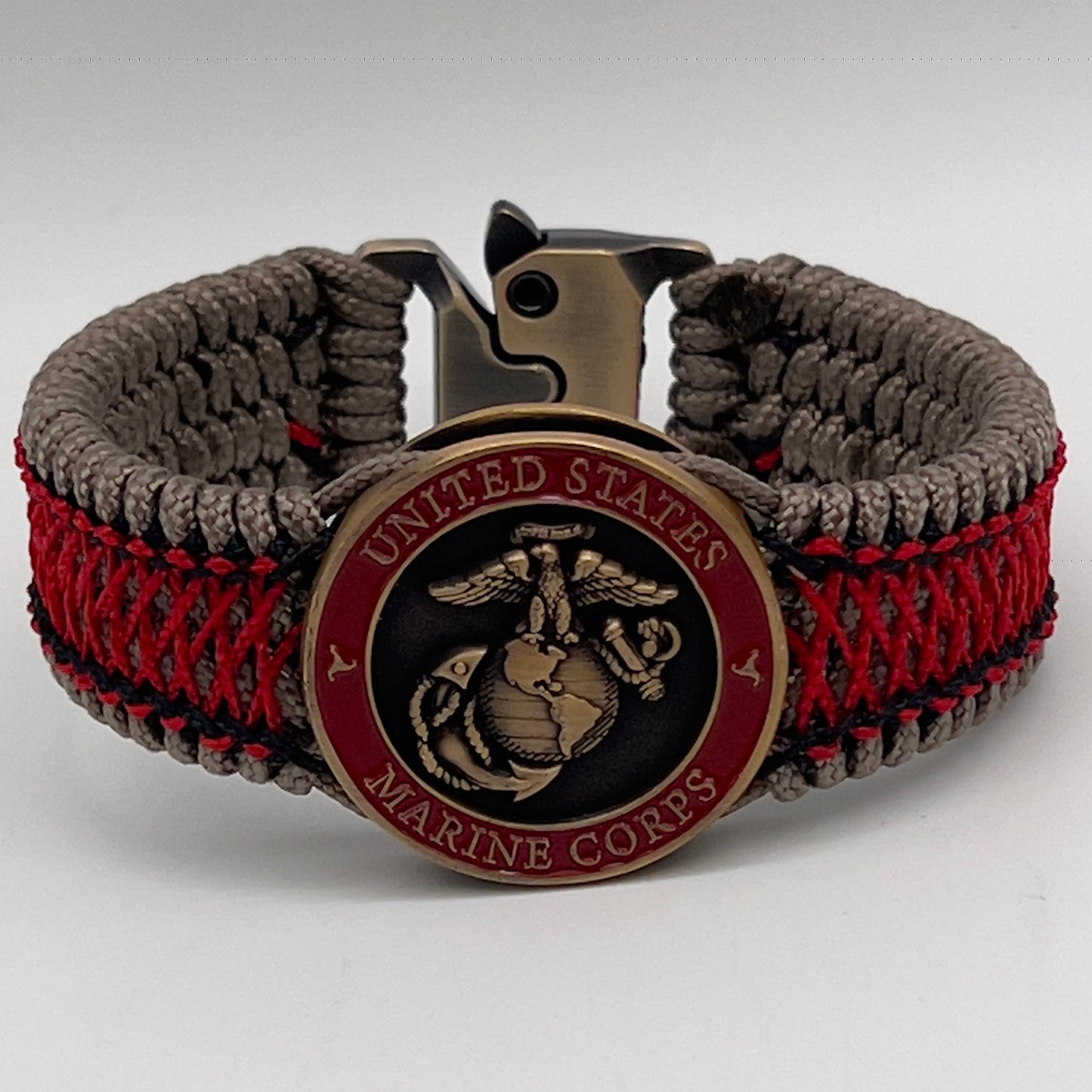 Thin, medium width, flexible and comfortable braided United States Marine Corps bracelet featuring a 24K antique gold plated USMC Eagle Globe and Anchor medallion, a gold Cobra style tactical buckle and woven with Tan Type-1 paracord and Imperial Red and Black nano cord.