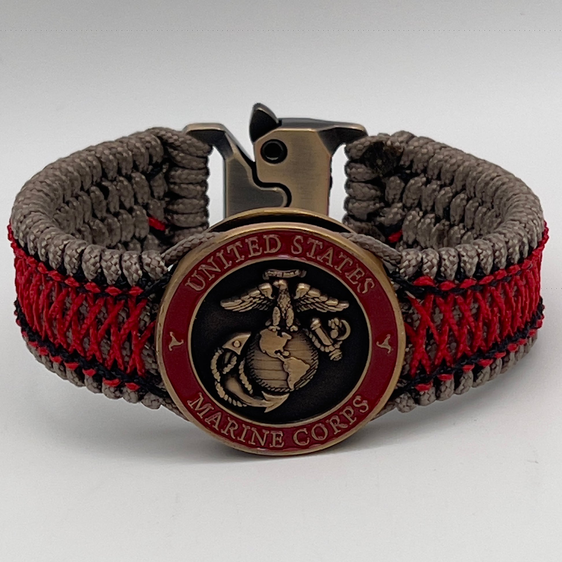 Thin, medium width, flexible and comfortable braided United States Marine Corps bracelet featuring a 24K antique gold plated USMC Eagle Globe and Anchor medallion, a gold Cobra style tactical buckle and woven with Tan Type-1 paracord and Imperial Red and Black nano cord.