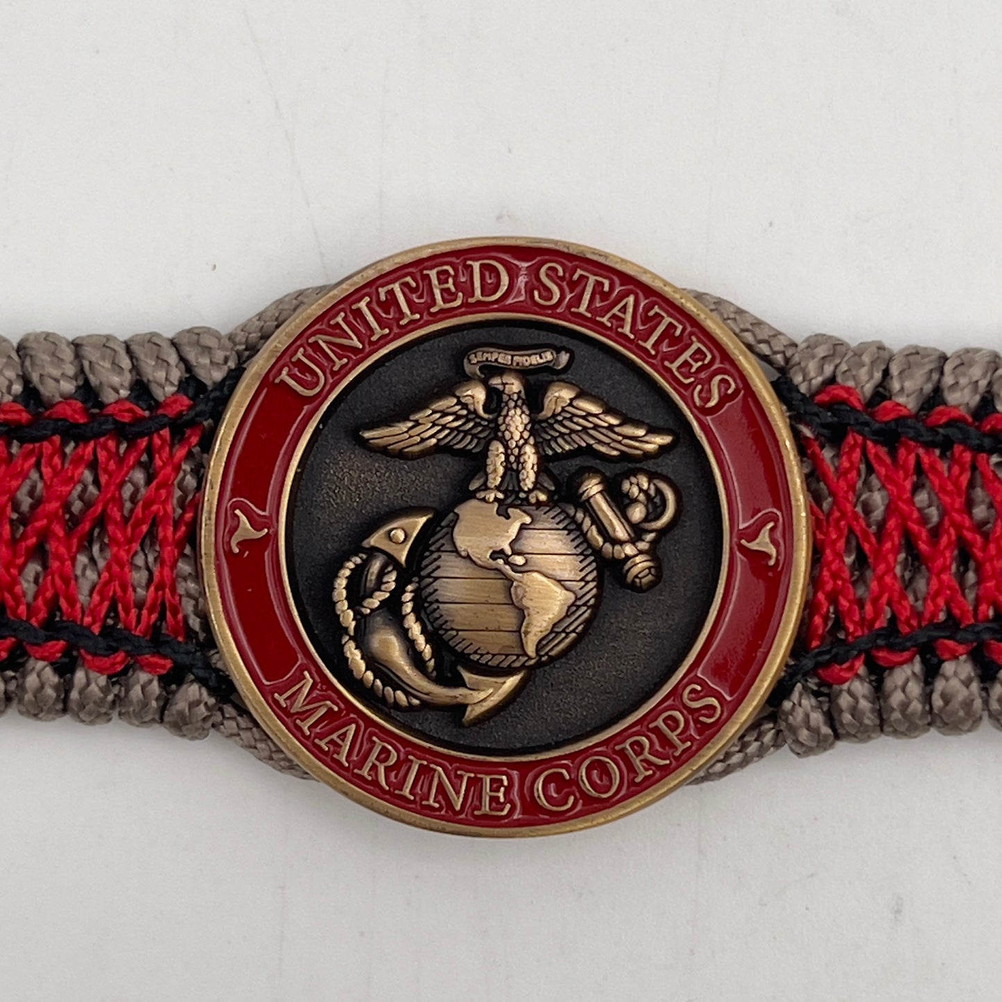 Thin, medium width, flexible and comfortable braided United States Marine Corps bracelet featuring a 24K antique gold plated USMC Eagle Globe and Anchor medallion, a gold Cobra style tactical buckle and woven with Tan Type-1 paracord and Imperial Red and Black nano cord.