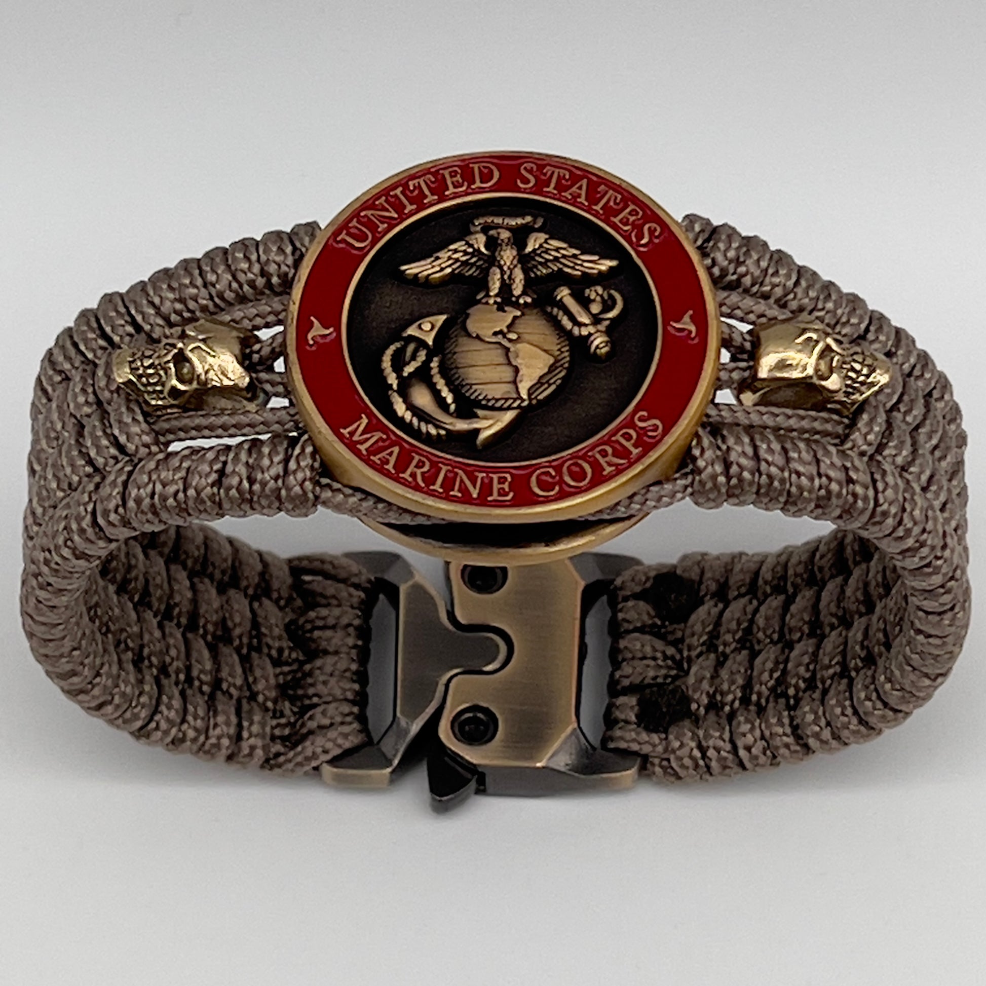 Thin, medium width, flexible and comfortable braided United States Marine Corps bracelet featuring a 24K antique gold plated USMC officer Eagle Globe and Anchor medallion, two gold plated skulls, a gold Cobra style tactical buckle and woven with tan Type-1 paracord.