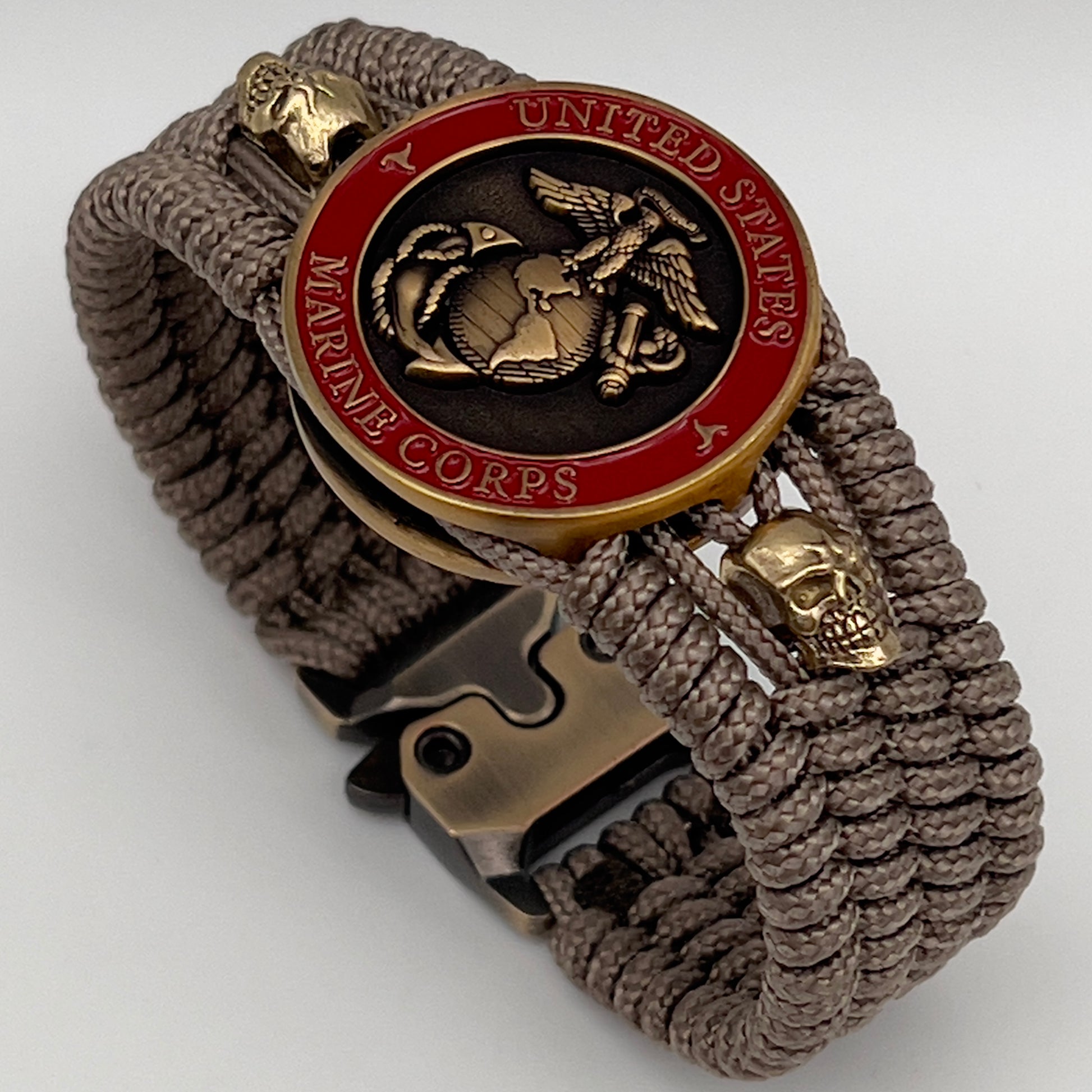 Thin, medium width, flexible and comfortable braided United States Marine Corps bracelet featuring a 24K antique gold plated USMC officer Eagle Globe and Anchor medallion, two gold plated skulls, a gold Cobra style tactical buckle and woven with tan Type-1 paracord.