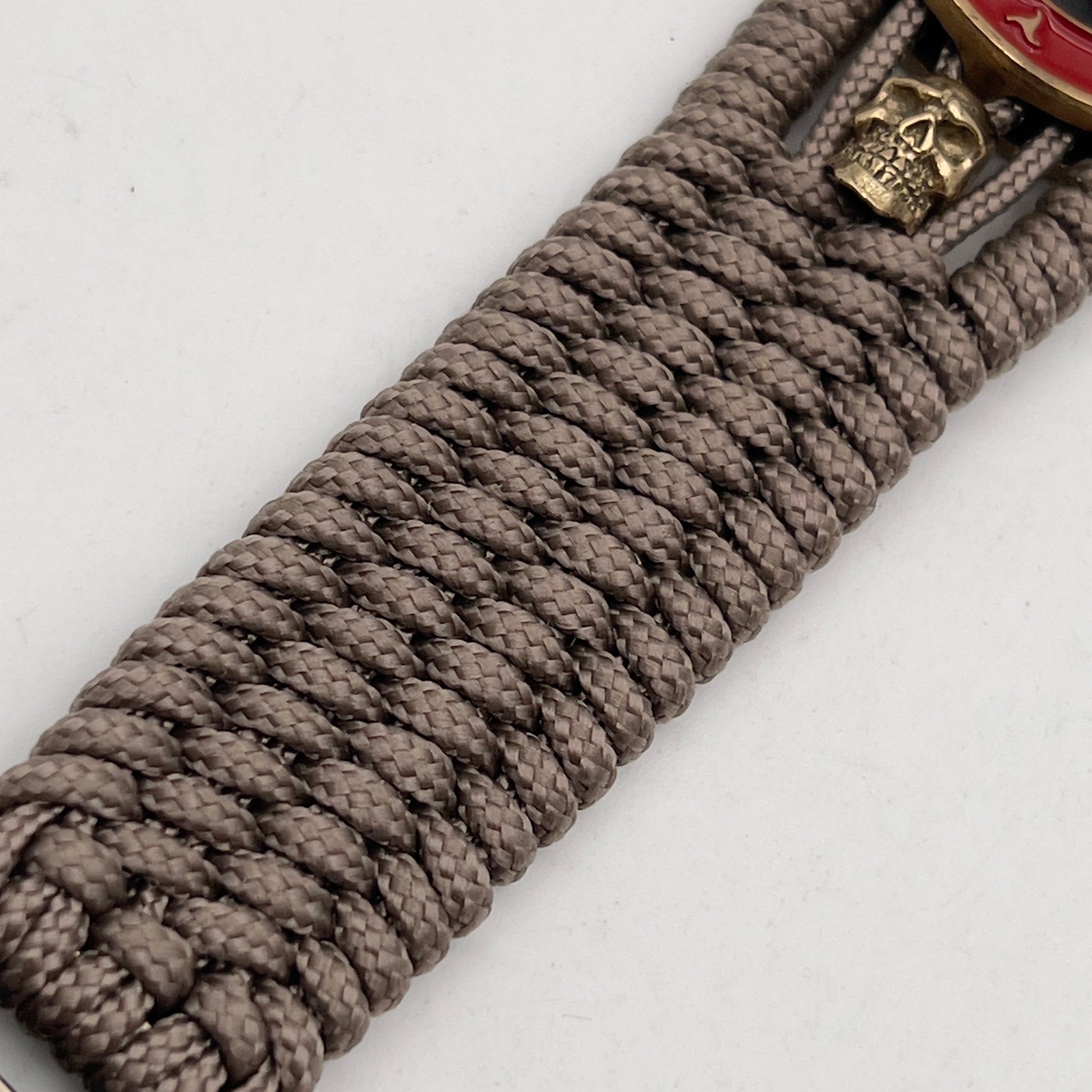 Thin, medium width, flexible and comfortable braided United States Marine Corps bracelet featuring a 24K antique gold plated USMC officer Eagle Globe and Anchor medallion, two gold plated skulls, a gold Cobra style tactical buckle and woven with tan Type-1 paracord.