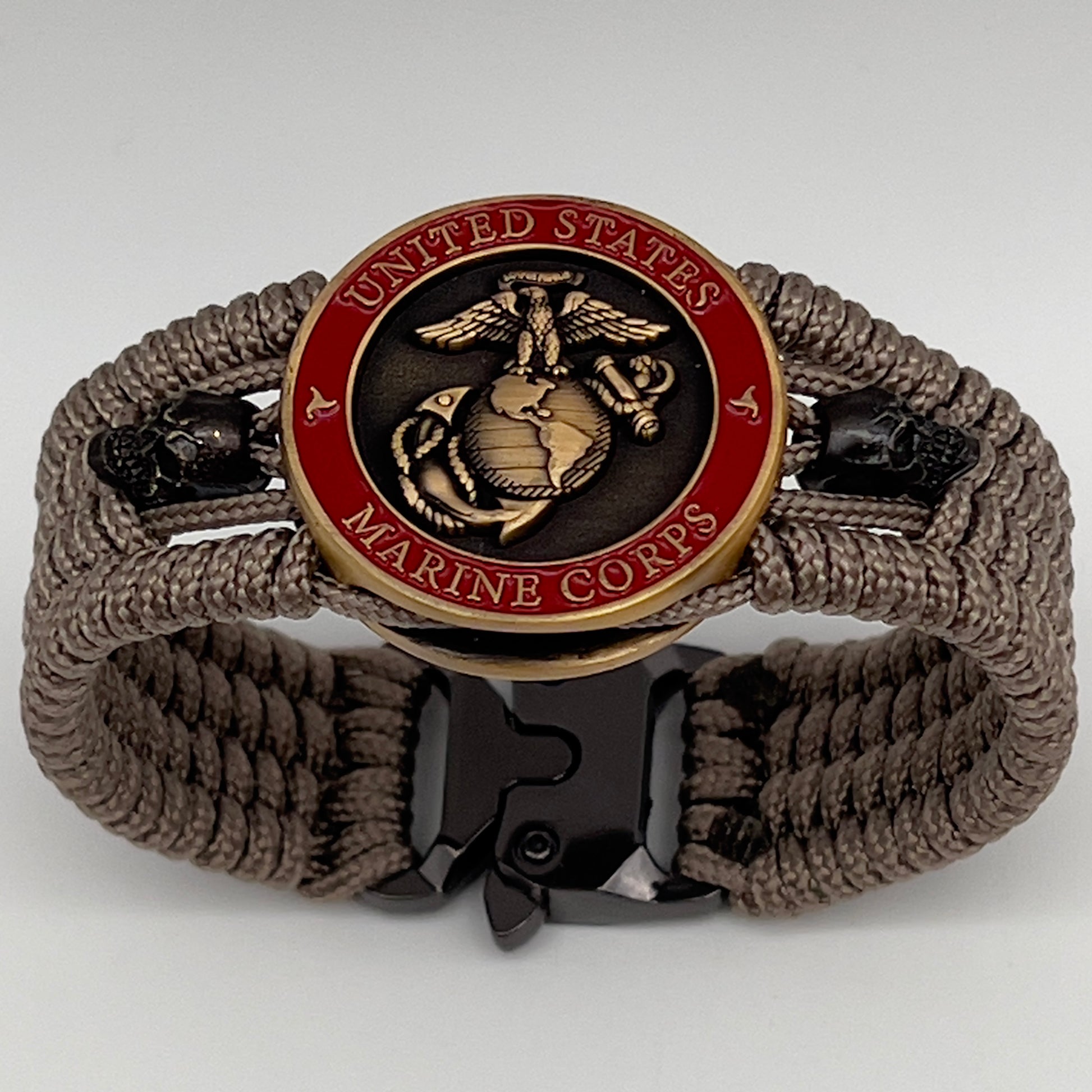 Thin, medium width, flexible and comfortable braided United States Marine Corps bracelet featuring a 24K antique gold plated USMC officer Eagle Globe and Anchor medallion, two black skulls, a black Cobra style tactical buckle and woven with tan Type-1 paracord.