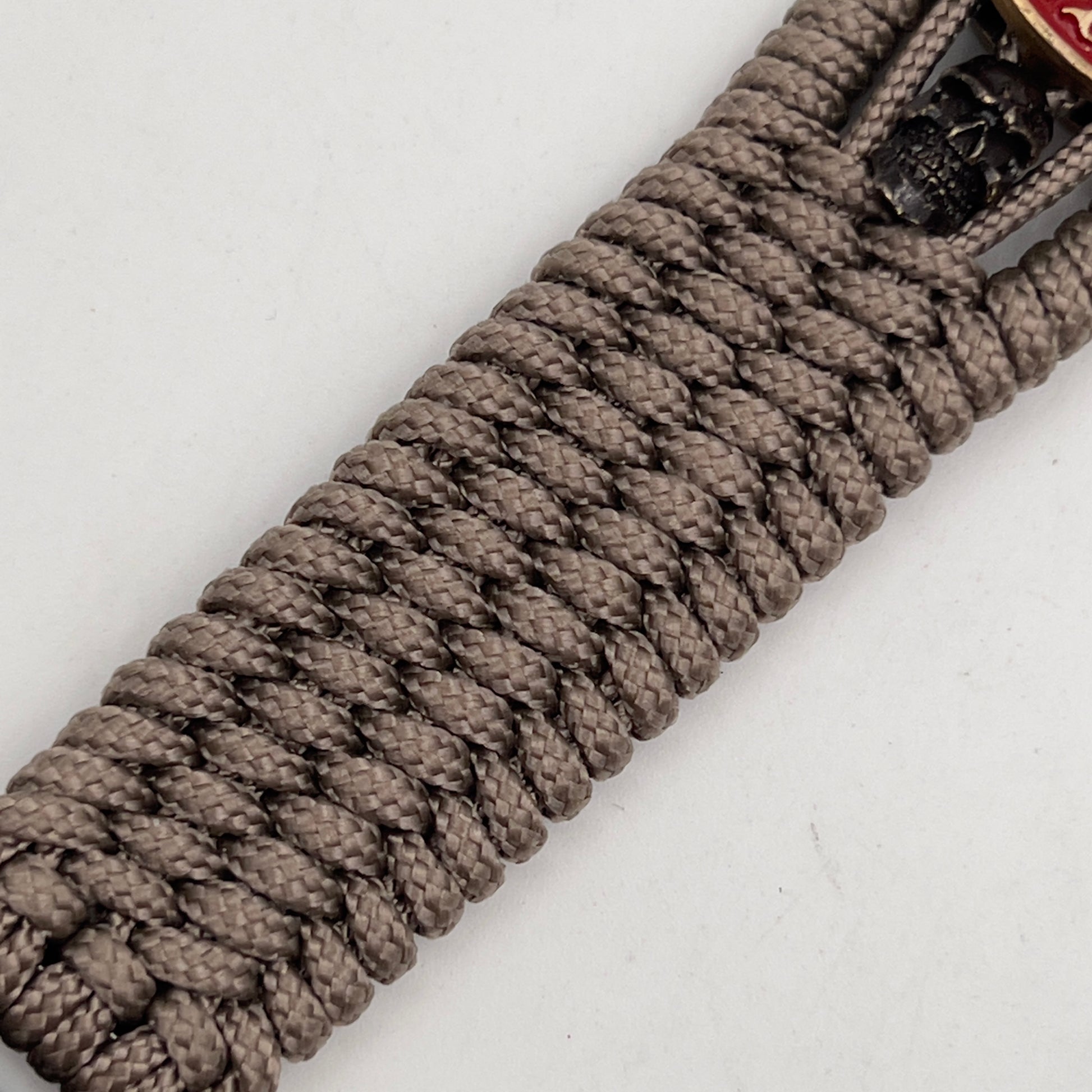 Thin, medium width, flexible and comfortable braided United States Marine Corps bracelet featuring a 24K antique gold plated USMC officer Eagle Globe and Anchor medallion, two black skulls, a black Cobra style tactical buckle and woven with tan Type-1 paracord.