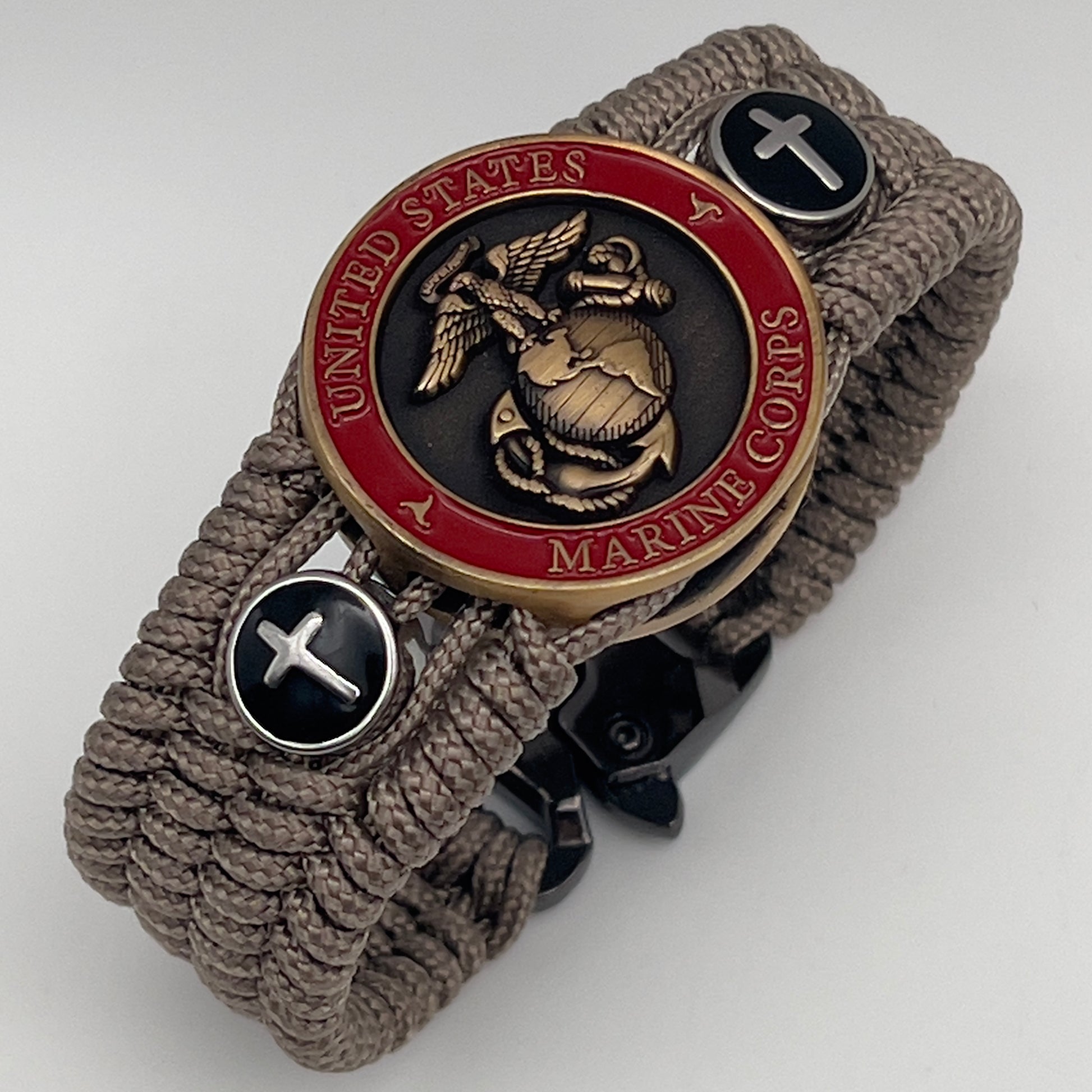 Thin, medium width, flexible and comfortable braided United States Marine Corps bracelet featuring a 24K antique gold plated USMC officer Eagle Globe and Anchor medallion, two Christian crosses, a black Cobra style tactical buckle and woven with Tan Type-1 paracord.