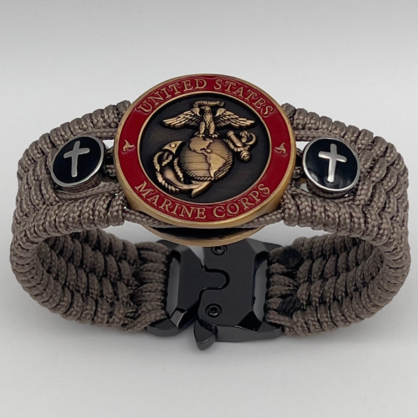 Thin, medium width, flexible and comfortable braided United States Marine Corps bracelet featuring a 24K antique gold plated USMC officer Eagle Globe and Anchor medallion, two Christian crosses, a black Cobra style tactical buckle and woven with Tan Type-1 paracord.