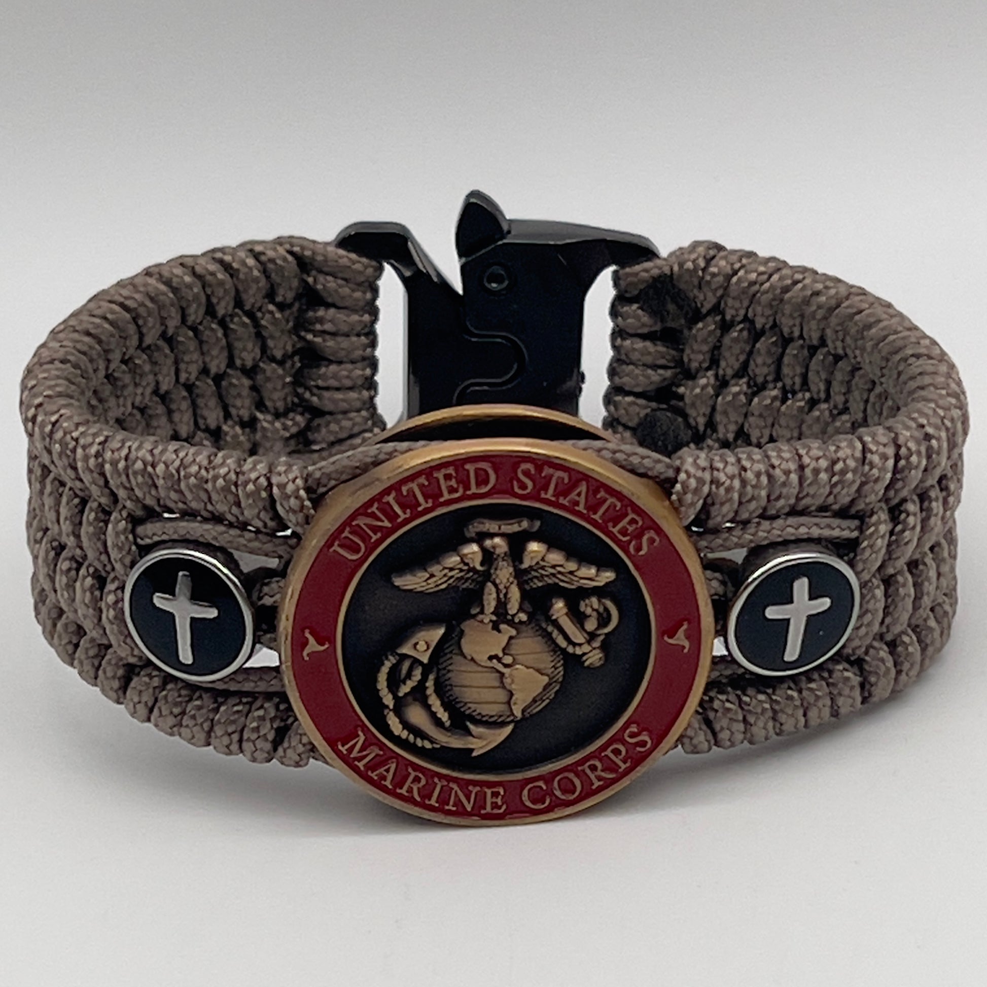 Thin, medium width, flexible and comfortable braided United States Marine Corps bracelet featuring a 24K antique gold plated USMC officer Eagle Globe and Anchor medallion, two Christian crosses, a black Cobra style tactical buckle and woven with Tan Type-1 paracord.