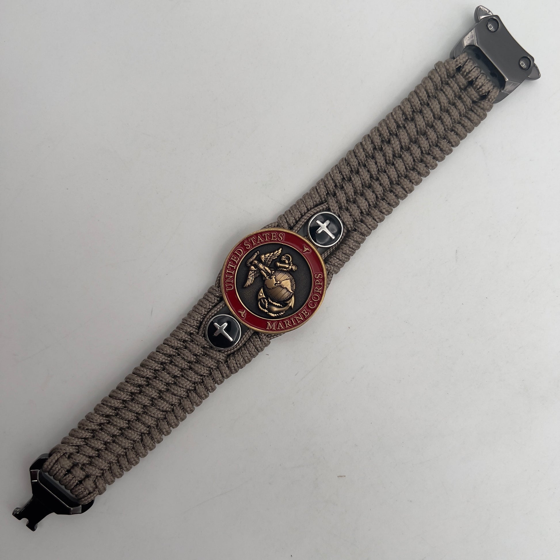 Thin, medium width, flexible and comfortable braided United States Marine Corps bracelet featuring a 24K antique gold plated USMC officer Eagle Globe and Anchor medallion, two Christian crosses, a black Cobra style tactical buckle and woven with Tan Type-1 paracord.