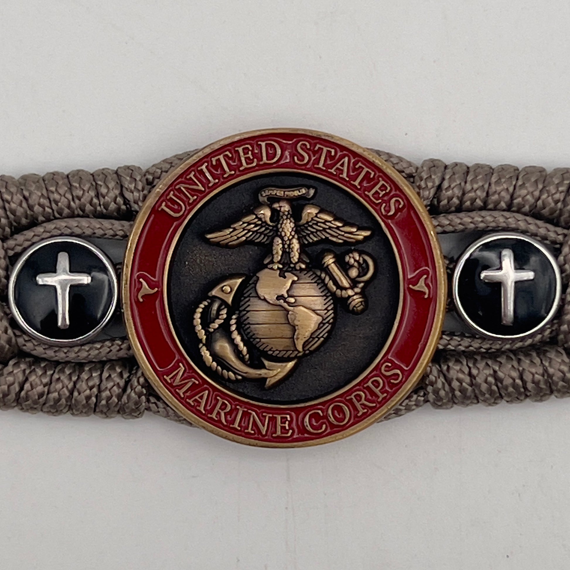 Thin, medium width, flexible and comfortable braided United States Marine Corps bracelet featuring a 24K antique gold plated USMC officer Eagle Globe and Anchor medallion, two Christian crosses, a black Cobra style tactical buckle and woven with Tan Type-1 paracord.