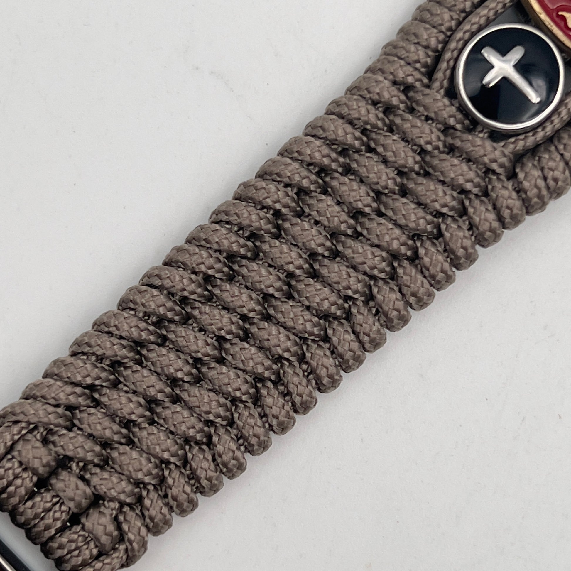 Thin, medium width, flexible and comfortable braided United States Marine Corps bracelet featuring a 24K antique gold plated USMC officer Eagle Globe and Anchor medallion, two Christian crosses, a black Cobra style tactical buckle and woven with Tan Type-1 paracord.